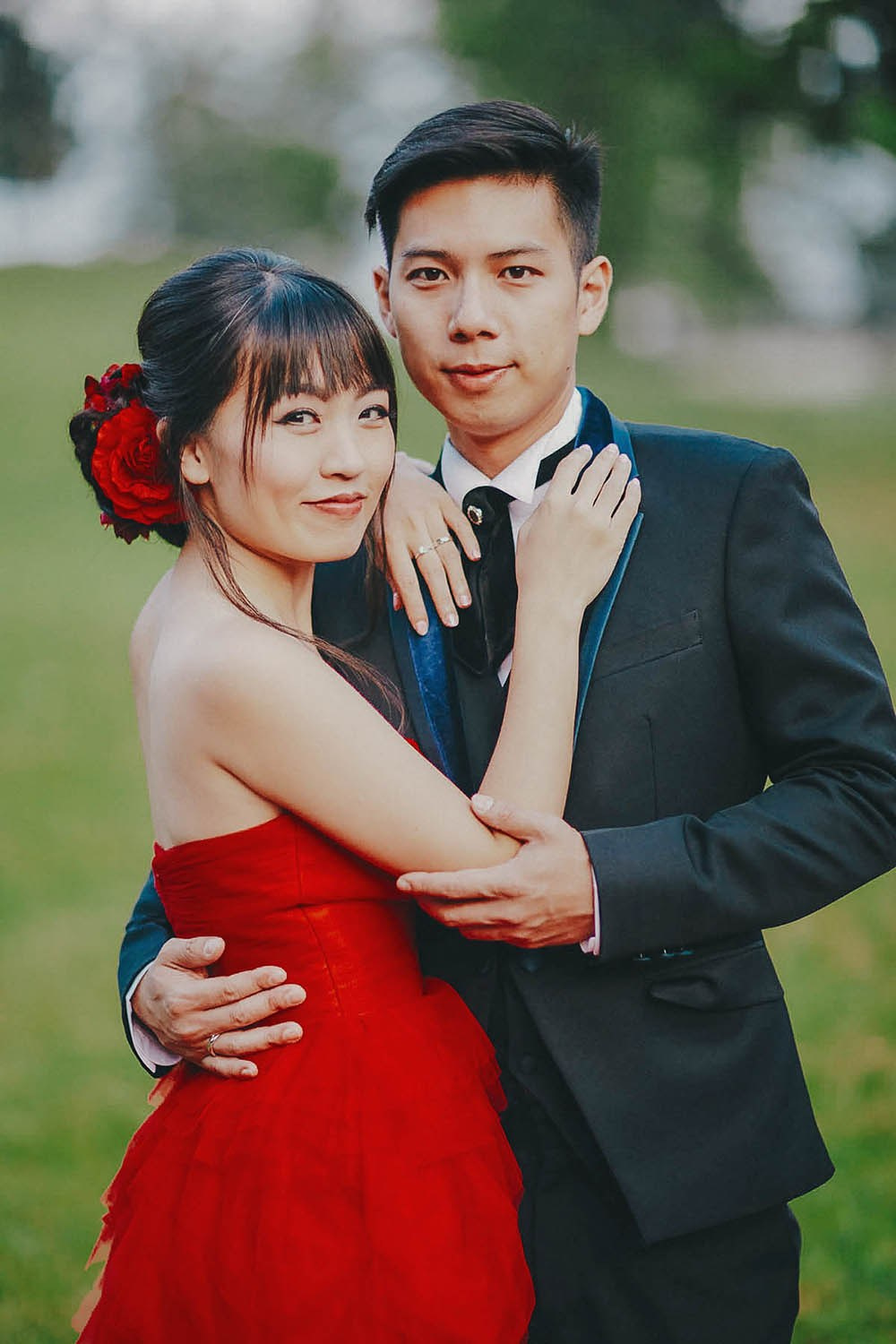 Asian newlyweds dressed in evening attire embrace in a garden setting in Prague - Kurt Vinion Photography