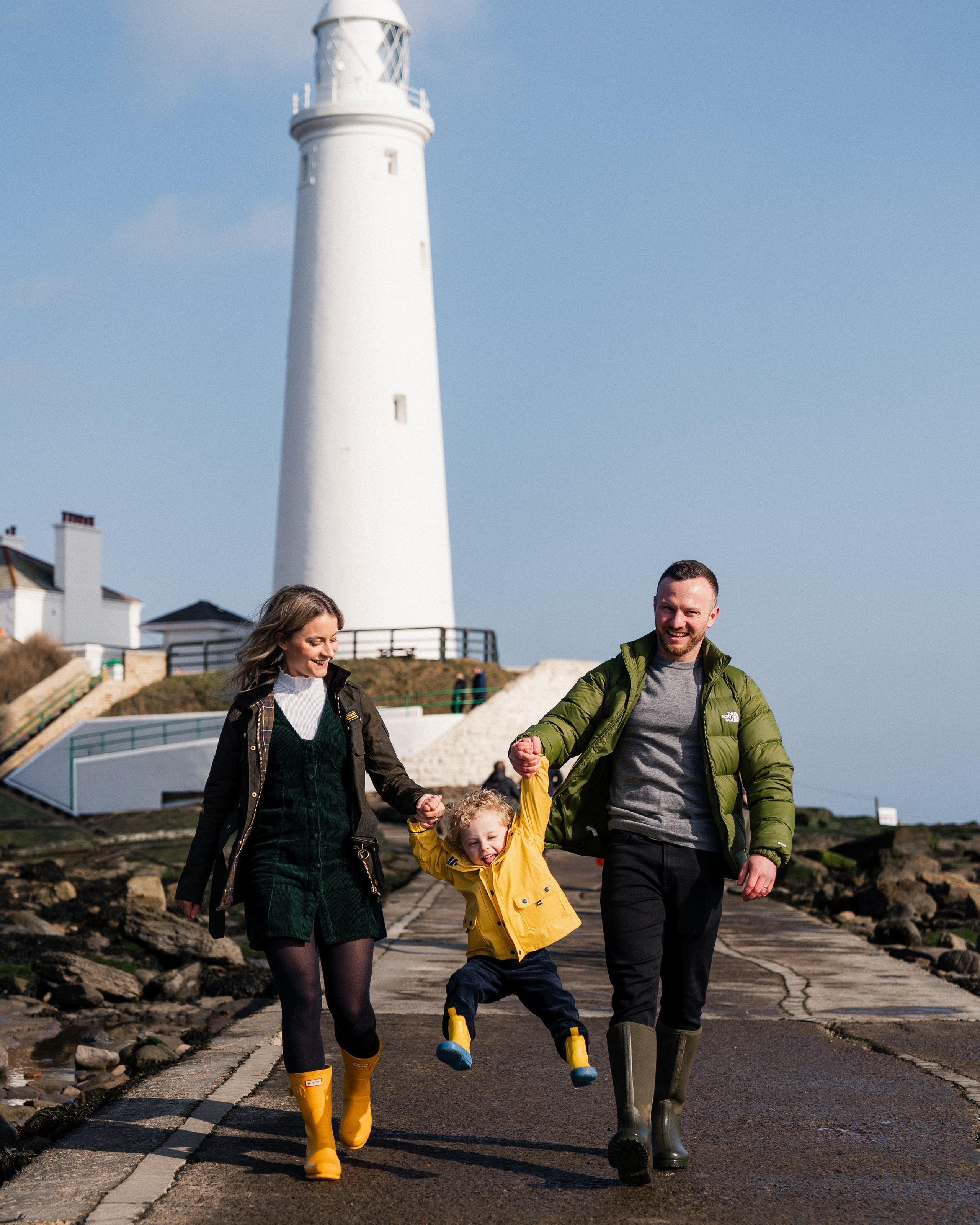 Family walking together near St Mary’s Lighthouse in Whitley Bay during a relaxed spring mini session by the sea
