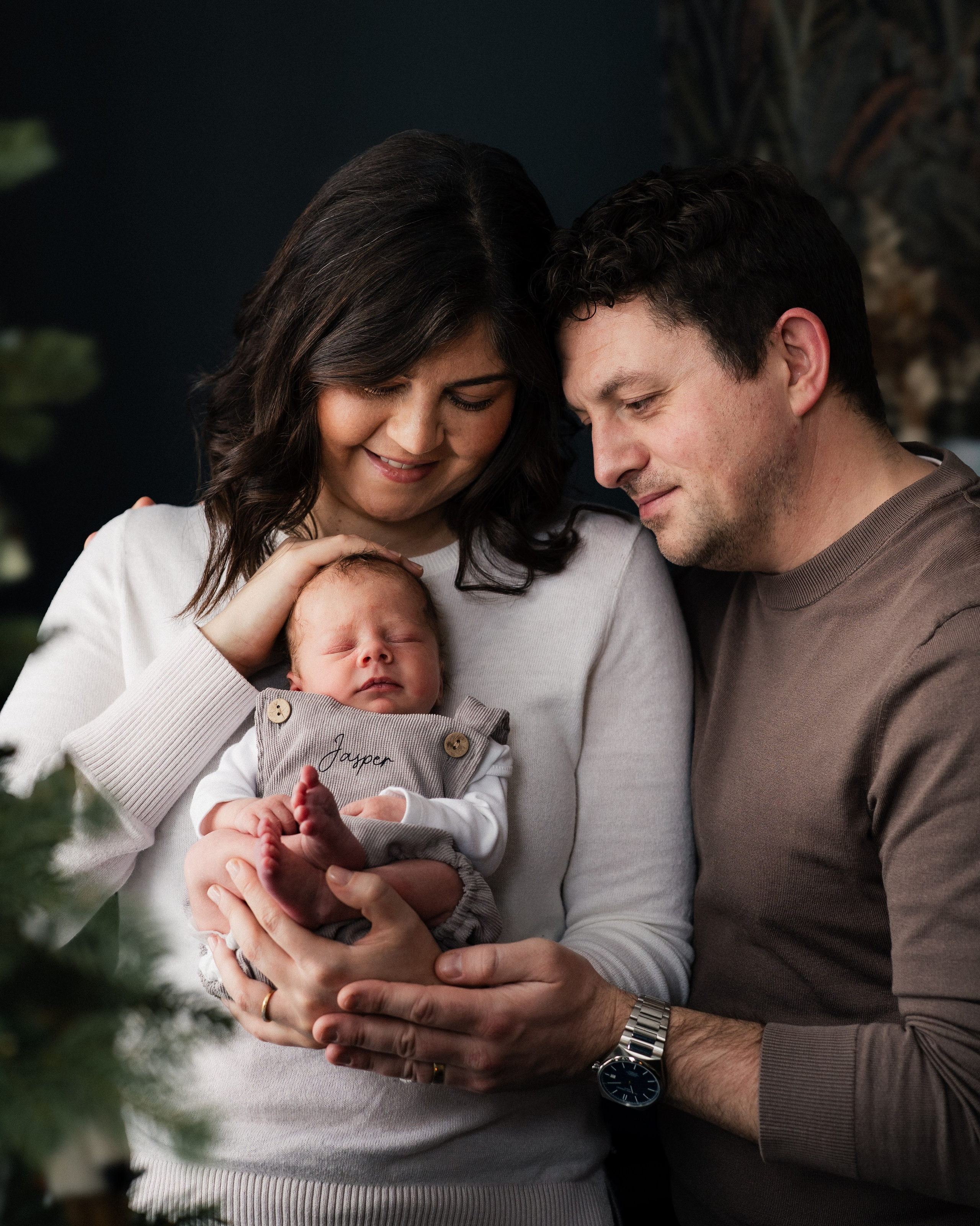 Parents holding their newborn baby during a cozy in-home newborn photoshoot in Whitley Bay, capturing genuine family connection