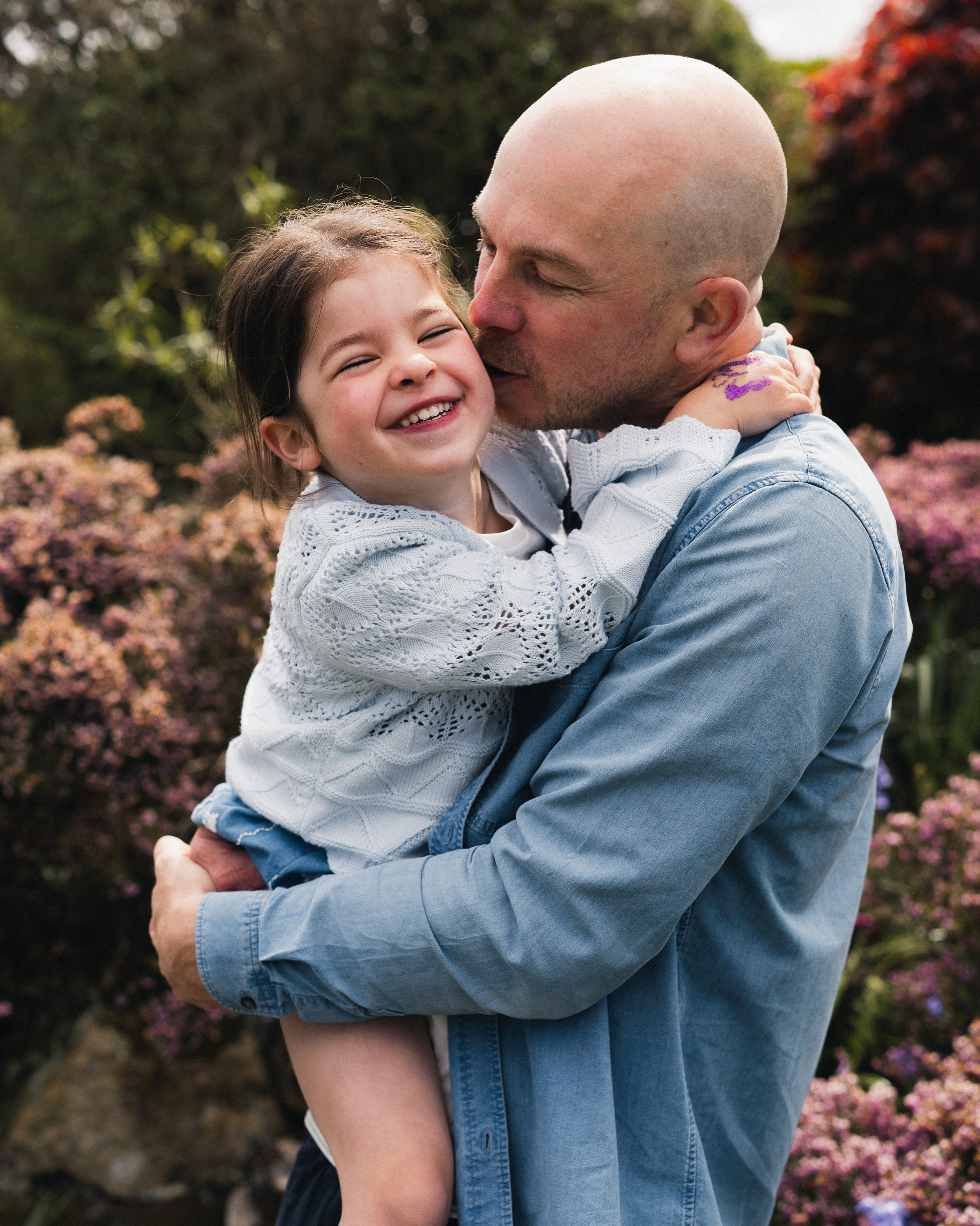 Father hugging his smiling daughter during a relaxed outdoor family photography session in Newcastle upon Tyne.