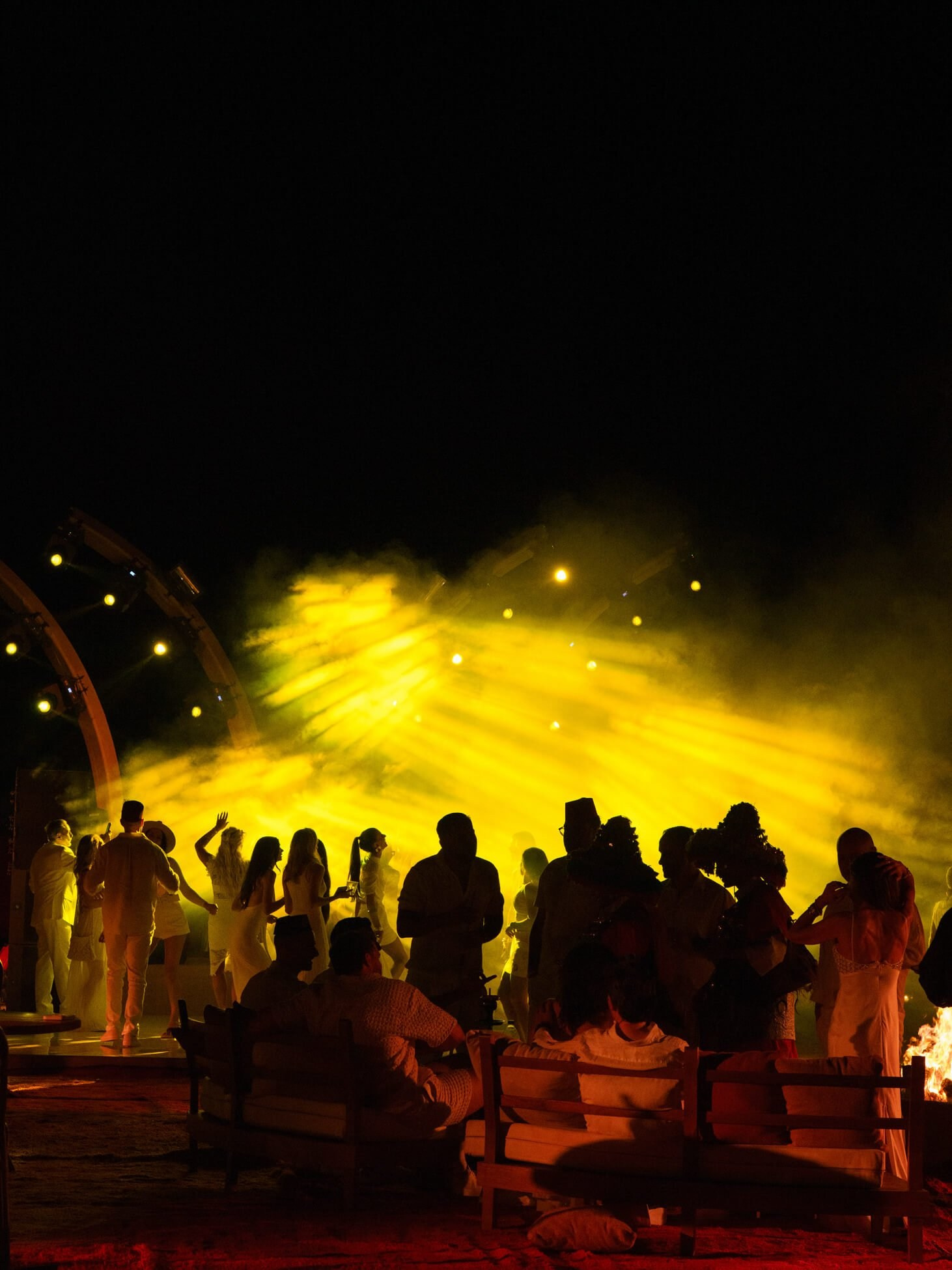 Guests dancing under yellow stage lights at desert wedding party
