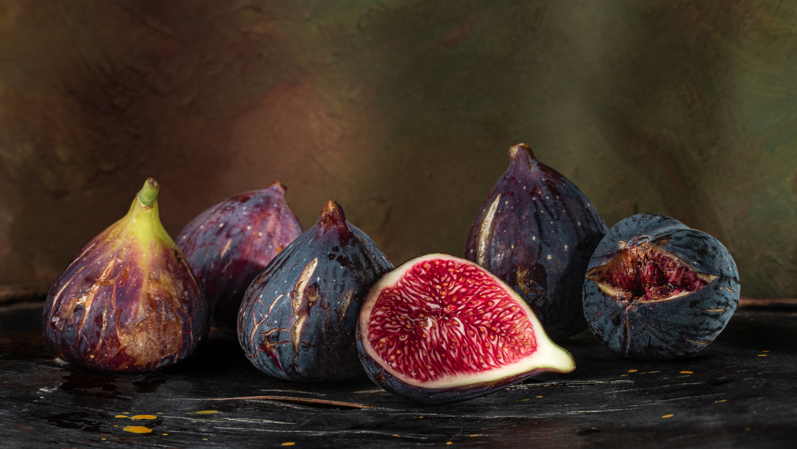 Təbii teksturalı fon üzərində kəsilmiş və bütöv əncirlərdən ibarət klassik natürmort qida kompozisiyası