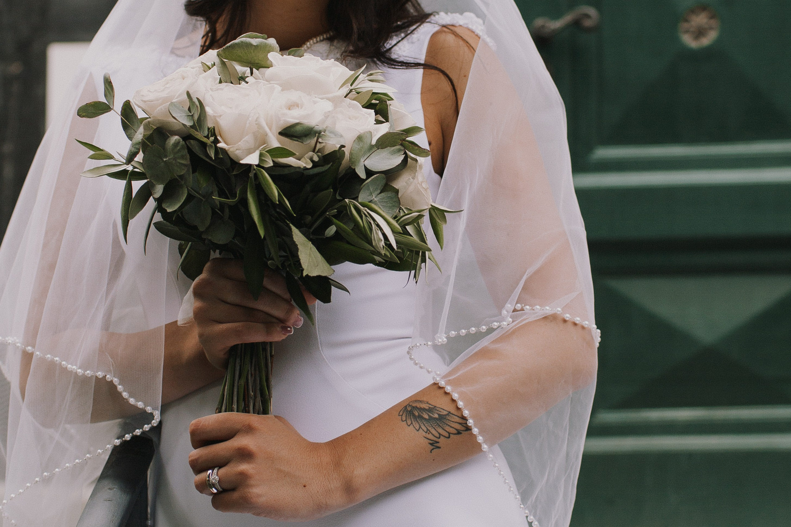 "Braut hällt den Blumenstrauß aus weißen Rosen" "Nahaufnahme" "Flügel Tatoo"