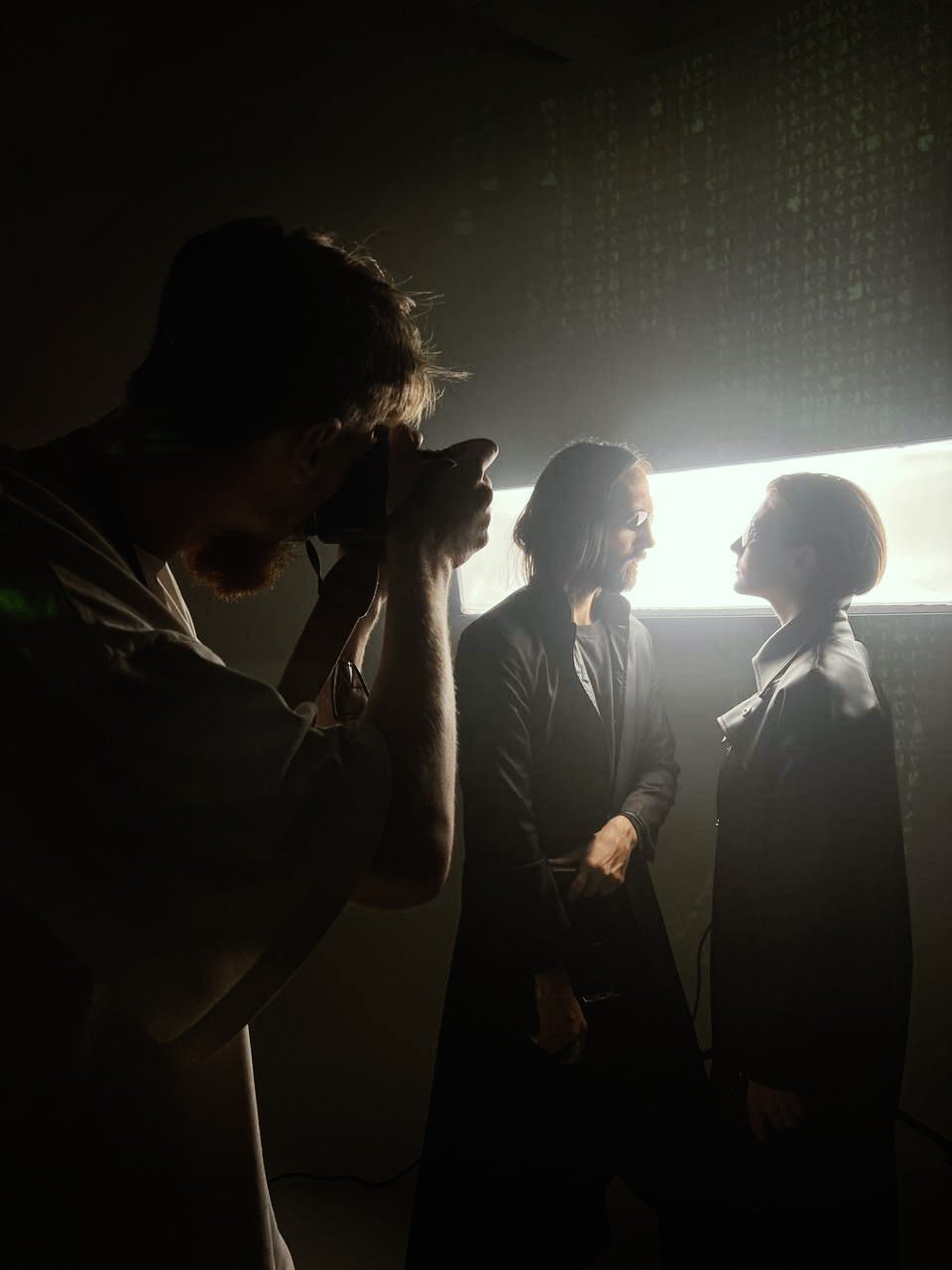 Фотограф фотографирует двух моделей в стиле матрица 