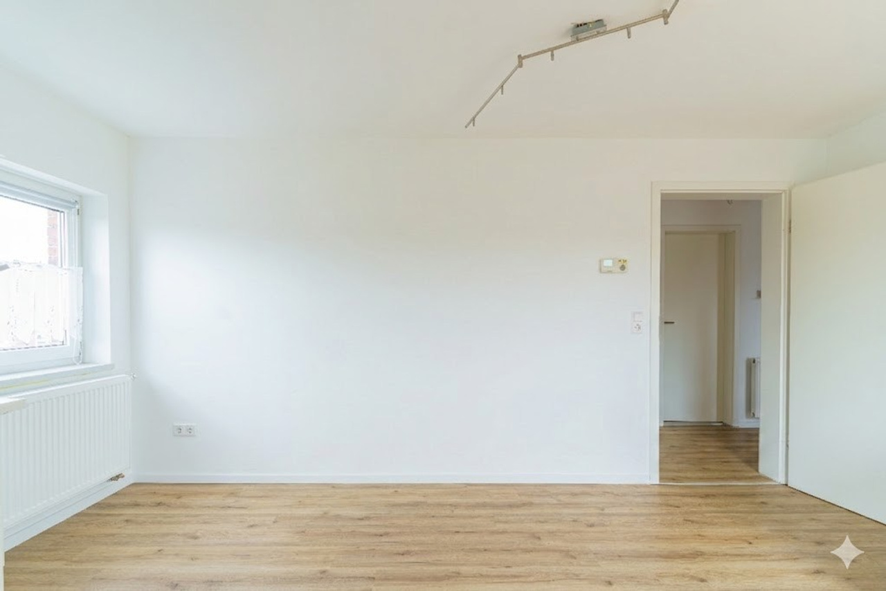 Vorher-Nachher Immobilienfotografie: KI-leergeräumtes Zimmer (virtuelles Decluttering) mit Laminatboden und weißer Tür. Service von jade-visual.
