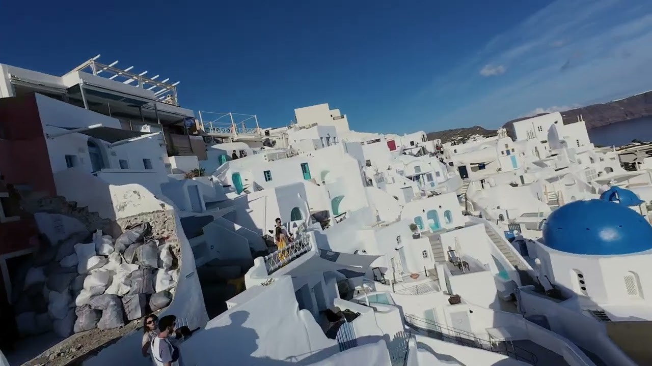 Whispers of Caldera Romance: Japanese Couple’s Enchanted Drone Journey at Mystique Santorini. Photographer in Santorini SokoLOVE Alex| Flying Dress Santorini