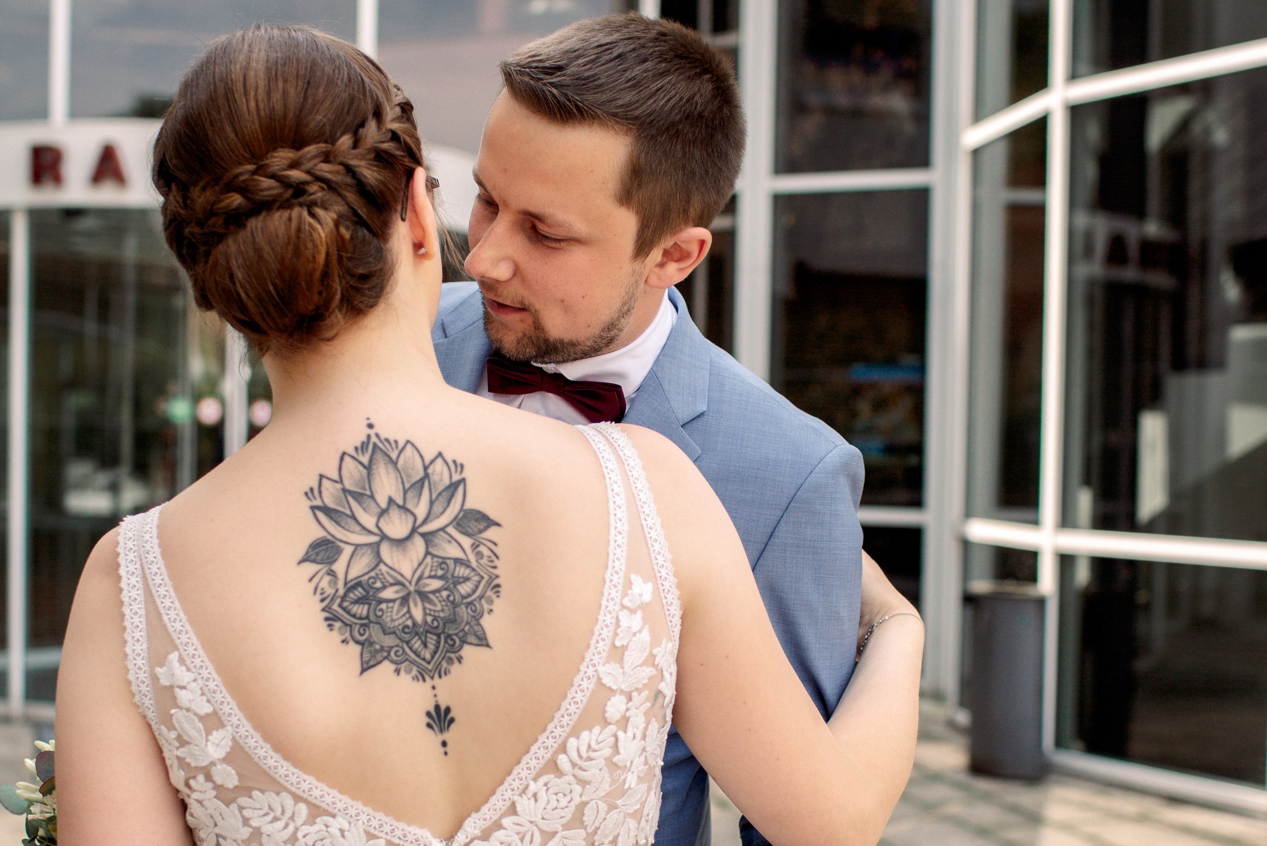 "Der Bräutigam küsst die Braut mit Tatoo auf dem Rücken vor dem Standesamt in Wallenhorst"