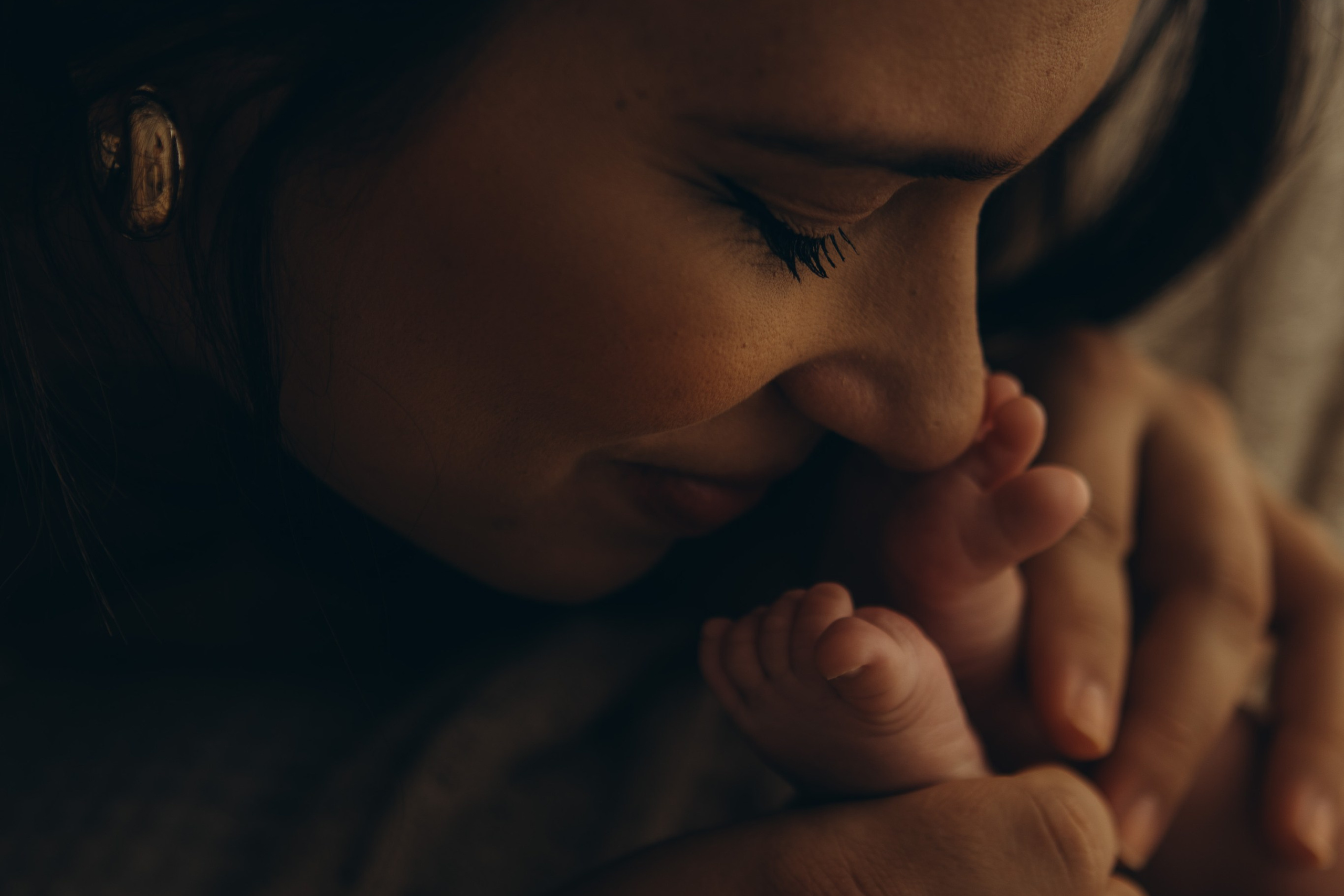 detalhe da mae cheirando o pé do bebê em ensaio newborn com luz natural em Sorocaba