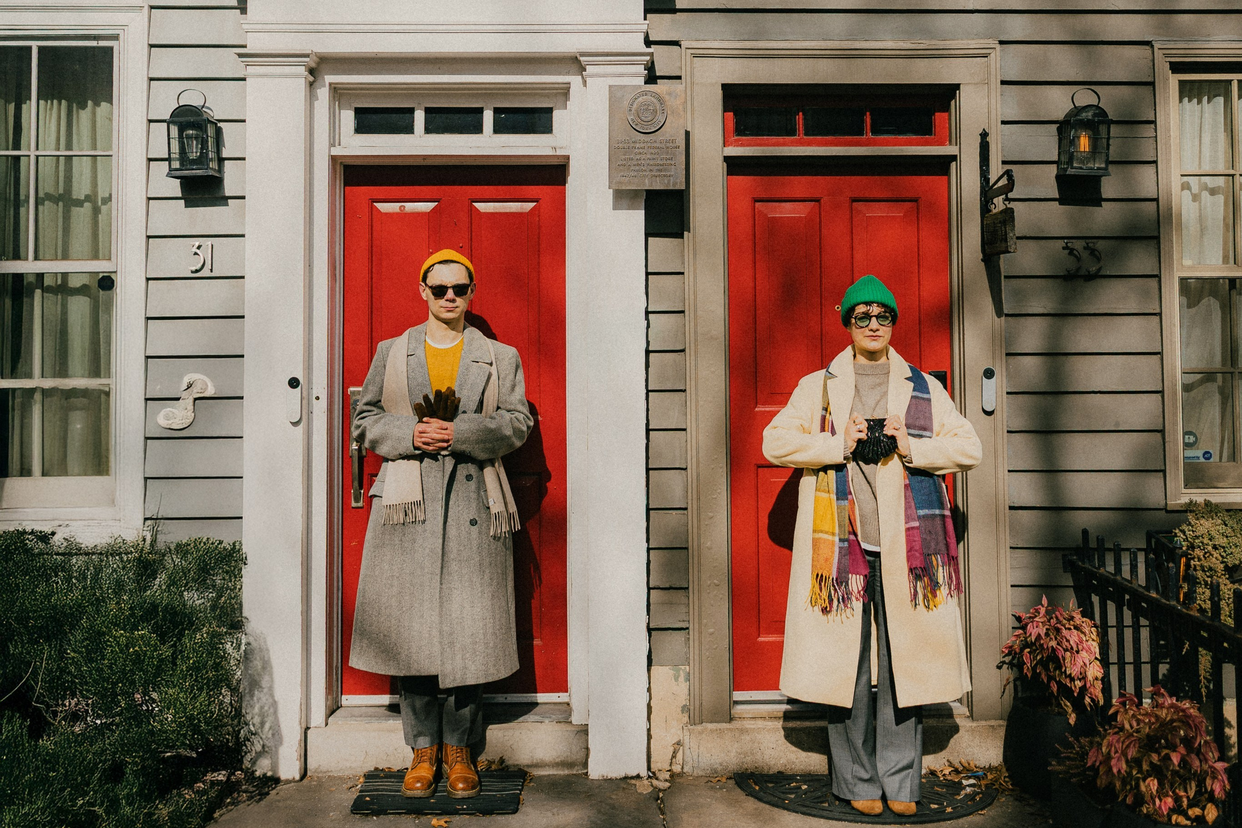 Деревянная стена из горизонтальных деревянных реек на просвет и на ее фоне висит обшарпанная лампа приглушенного кирпичного цвета