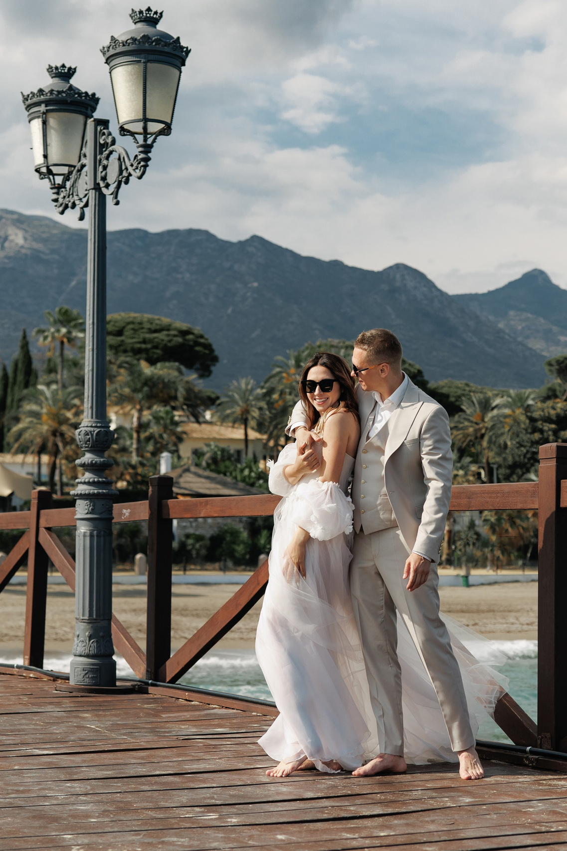 bride and groom in front of the sea and mountains and a lamp