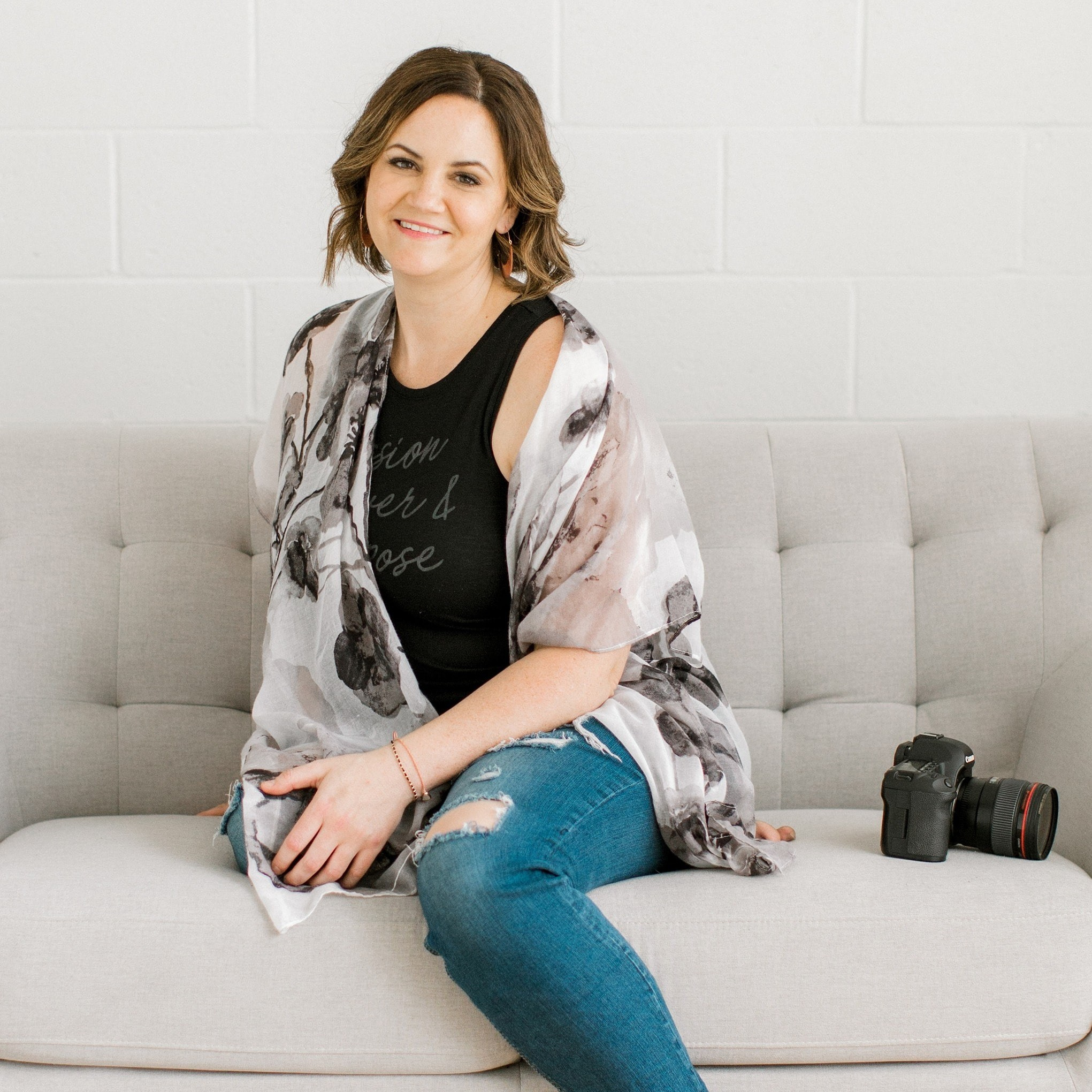 portrait of photographer sitting on couch with camera beside her on couch