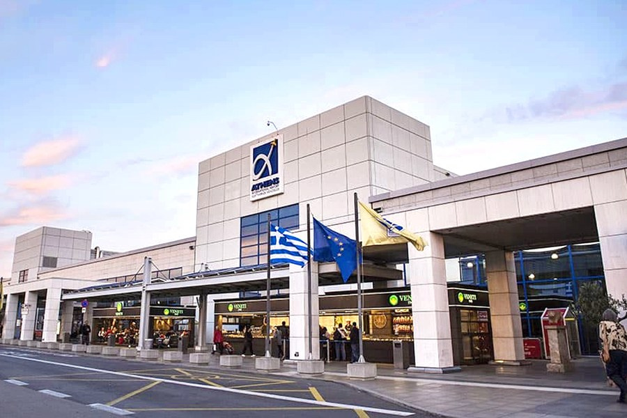 Athens International Airport (ATH) main terminal building with Greek and EU flags, symbolizing arrival and departure point for Athens travel.