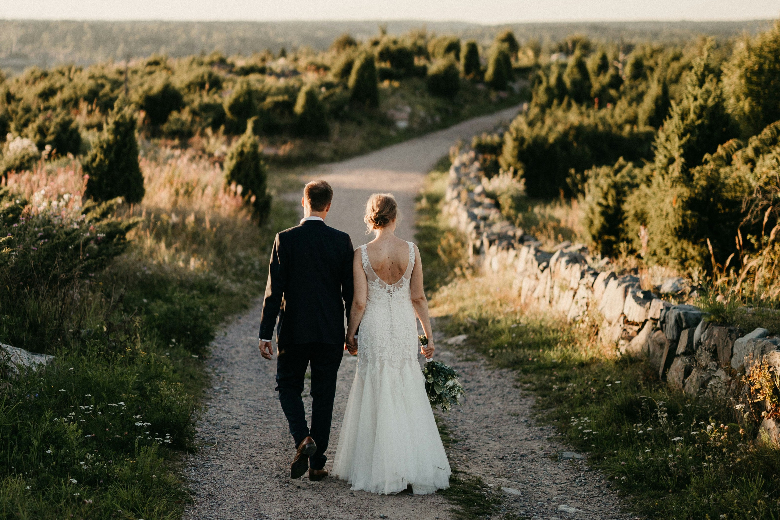 Bride and groom walking amidst rolling Tuscan hills.