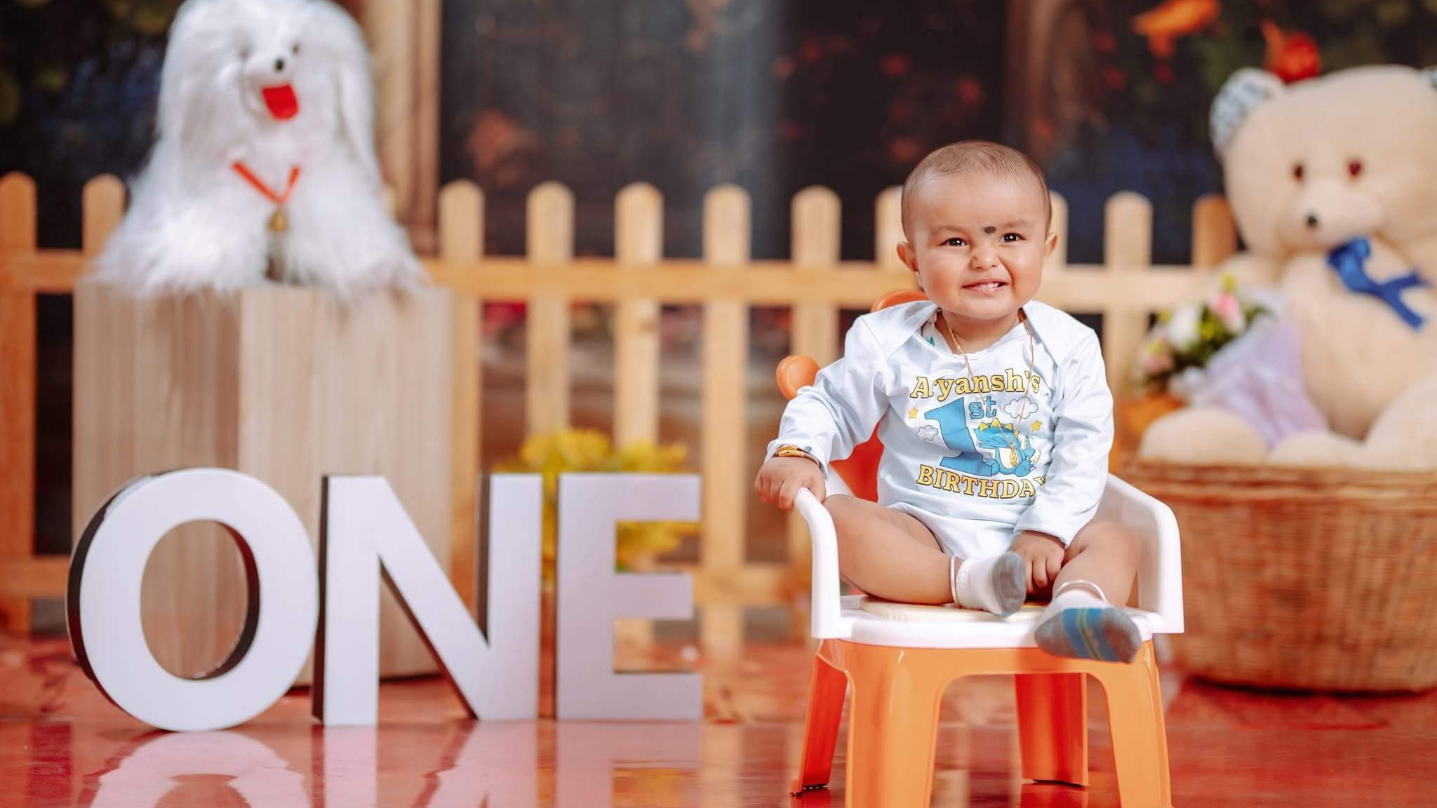 Baby boy sitting on a chair in a rustic birthday photo setup with a teddy bear Nepali baby birthday photoshoot.