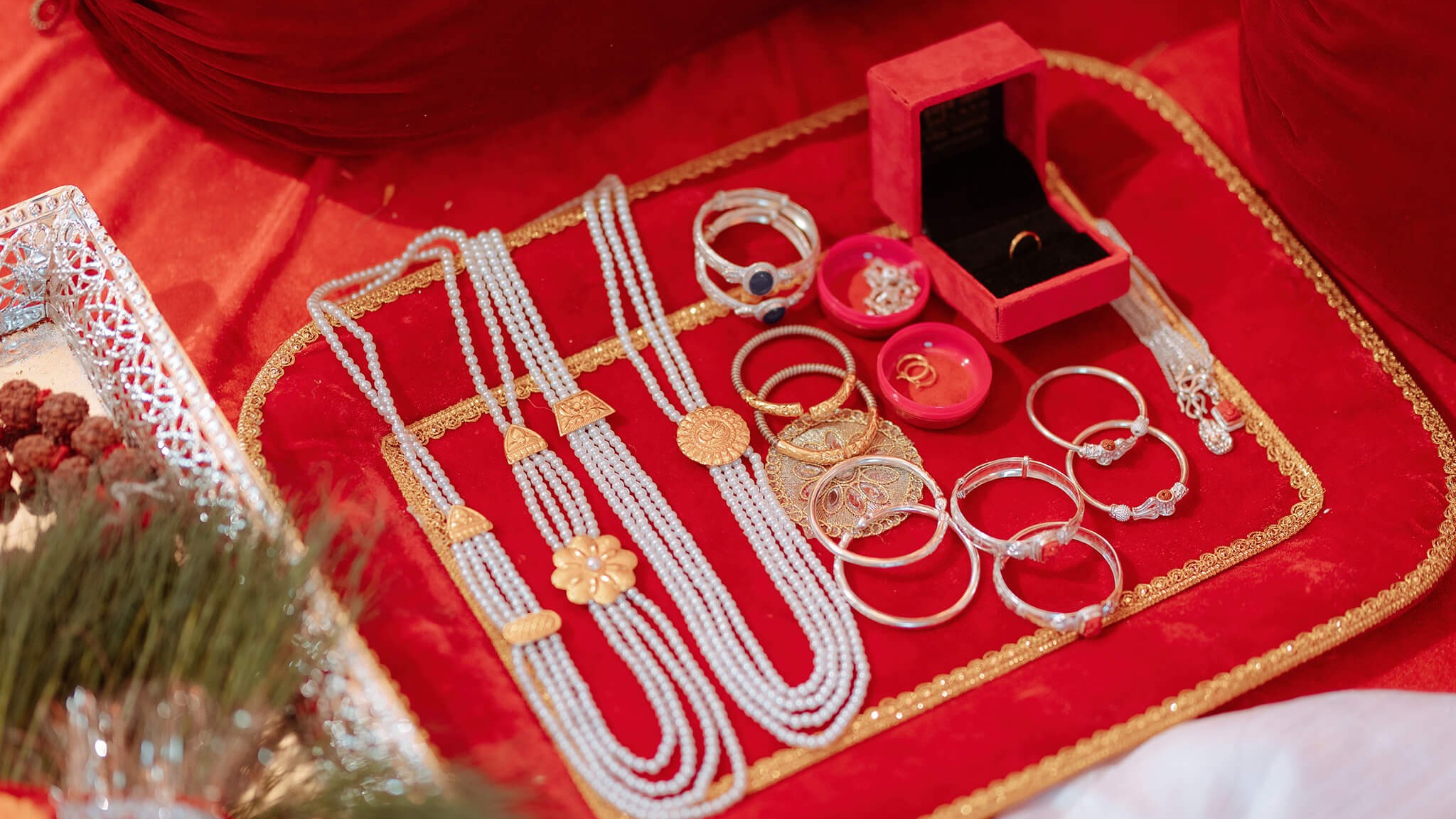 Traditional jewelry and ornaments arranged on a red cloth for a Pasni (Rice feeding) ceremony