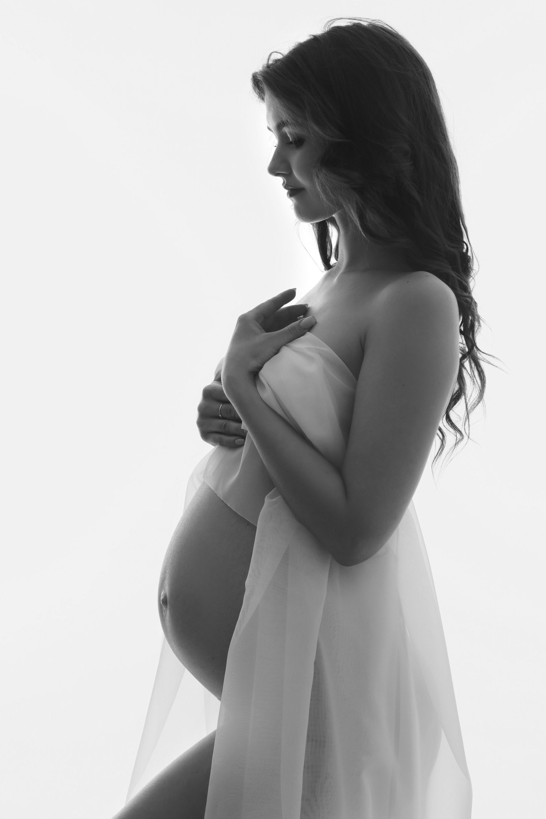 Sanftes und verträumtes Portrait einer werdenden Mutter in – emotionale Tiefe und innere Ruhe in einer kunstvollen, minimalistischen Inszenierung. Faszinierendes Frauenportrait mit fließendem Stoff – künstlerische Bewegung trifft auf ästhetische Fotografie mit luxuriösem Flair.