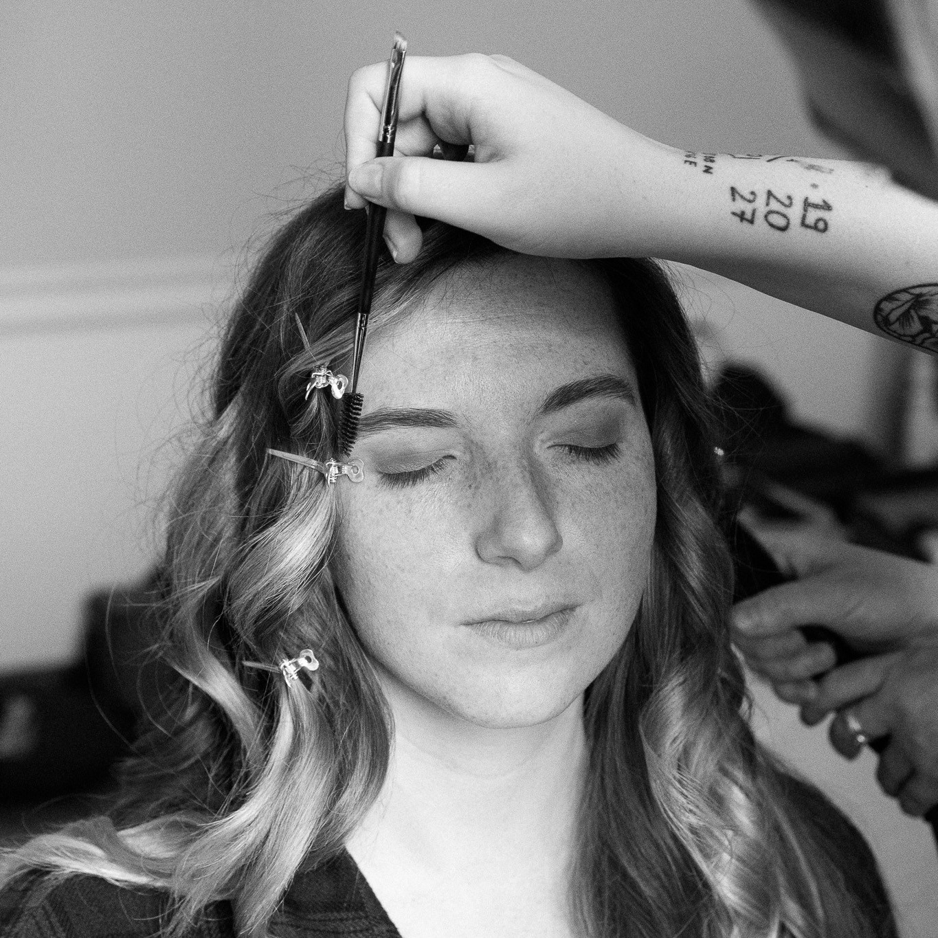 A professional makeup artist applying soft, natural makeup to a model before a photoshoot.