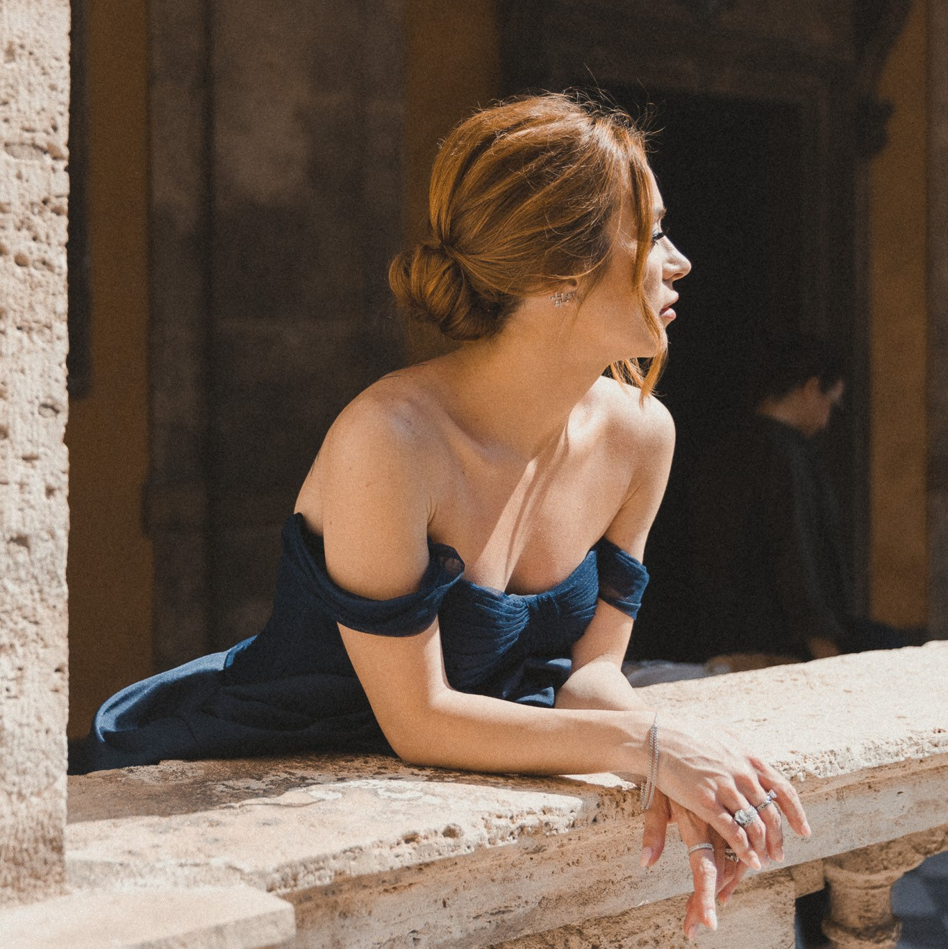 An elegant woman standing on the balcony during a photoshoot naturally posing.