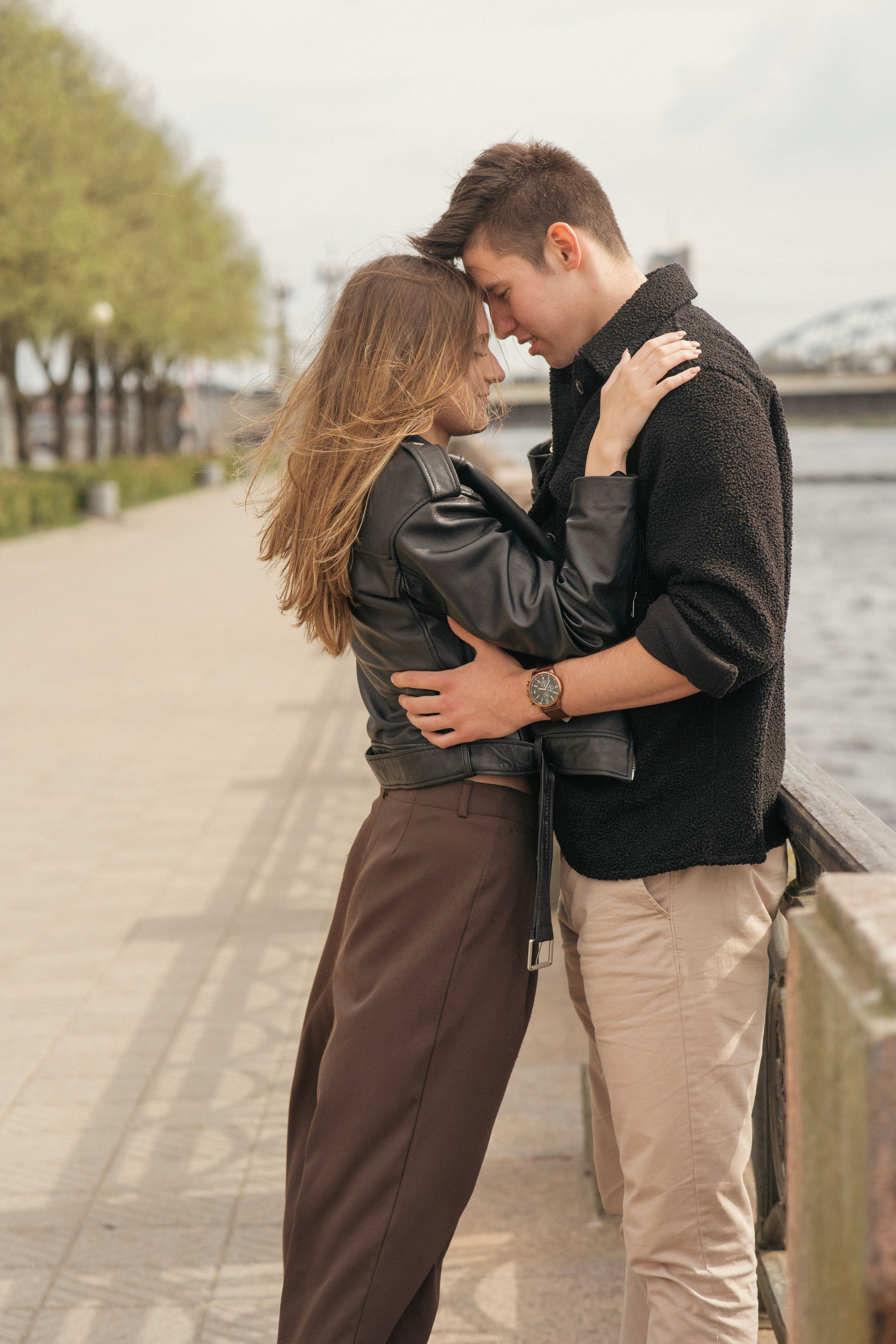 A couple stands on the seashore, watching the sunset – color portrait, love story photography