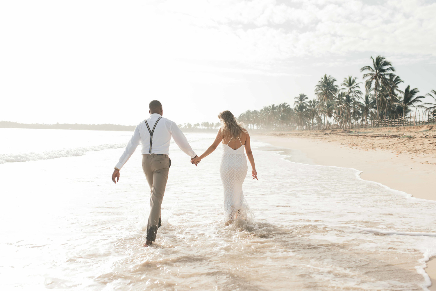 A bride leads her groom through the waves on Macau beach. 