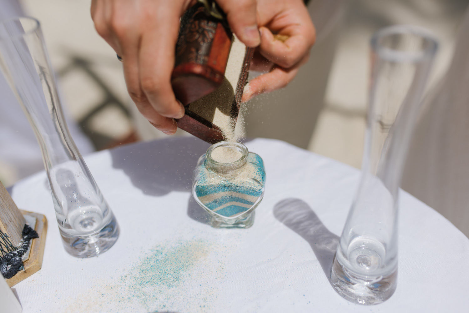 Во время песочной церемонии жених пересыпает песок в сосуд.