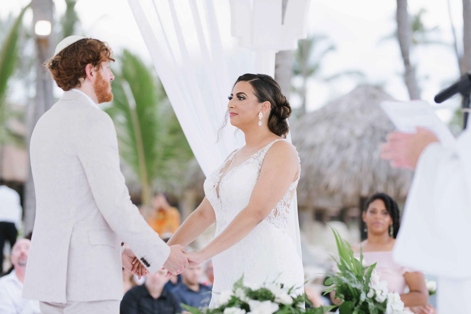 The bride and groom hold hands in a traditional Jewish wedding ceremony. 