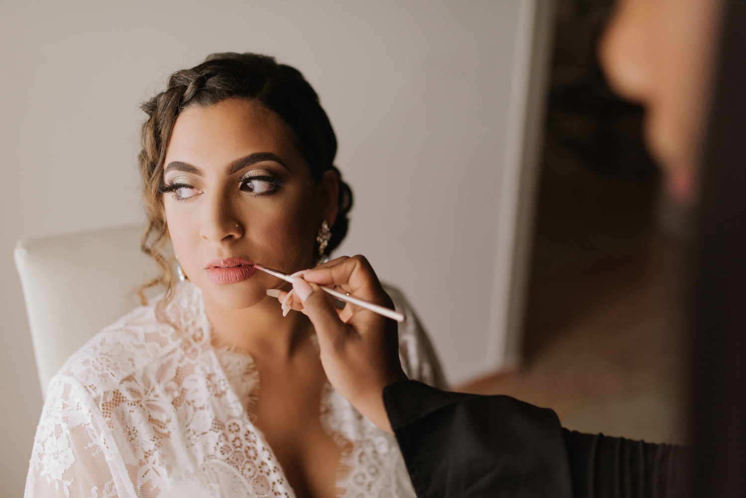 A makeup artist puts on bridal makeup for the bride. 