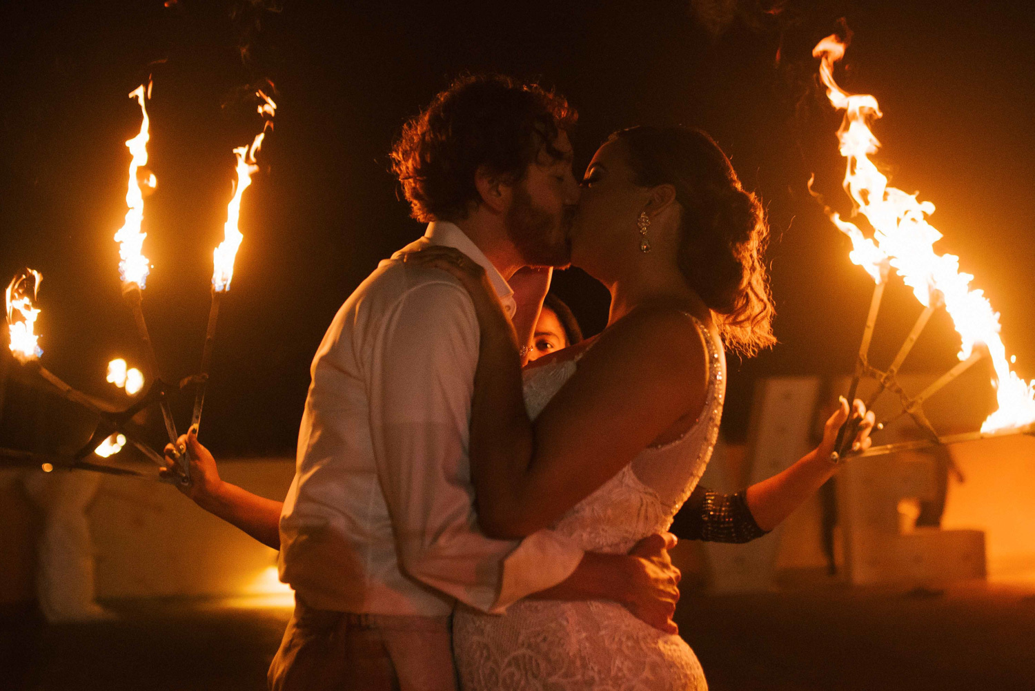 The bride and groom kiss each other during the fire show. 