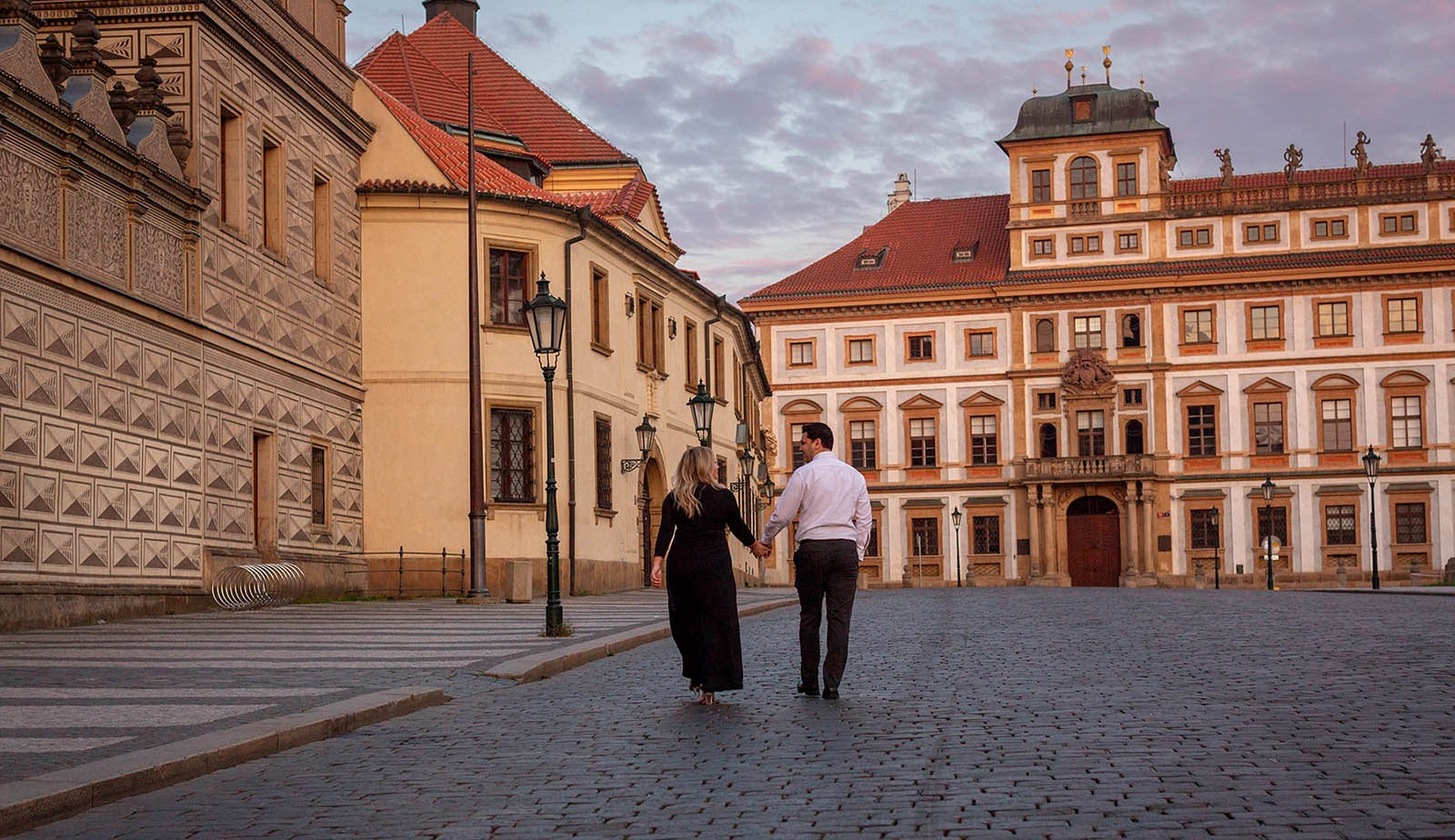 An American couple exploring the historic courtyards of Prague Castle alone at dawn