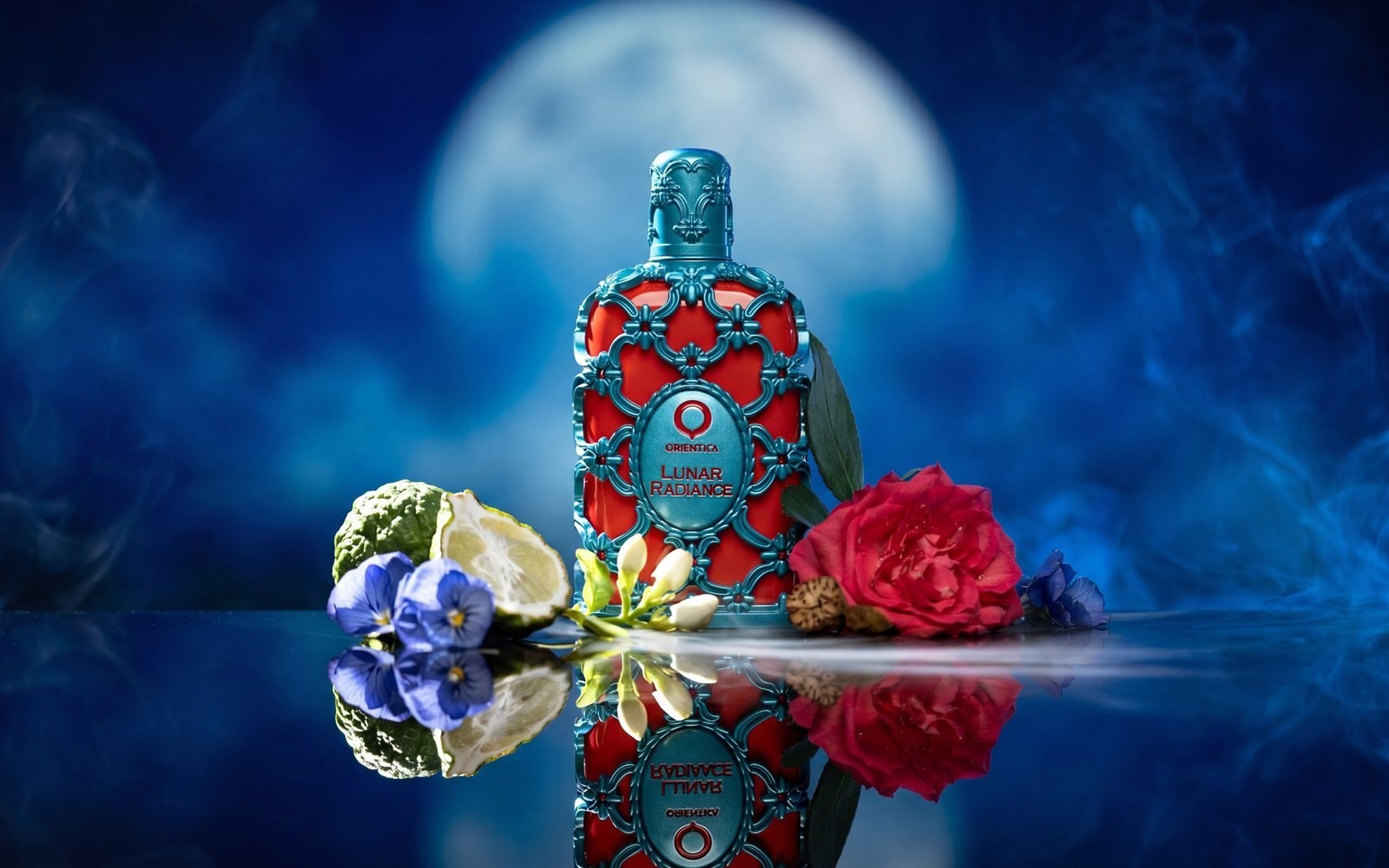 Decorative blue and red perfume bottle with flowers and a reflection against a blue background