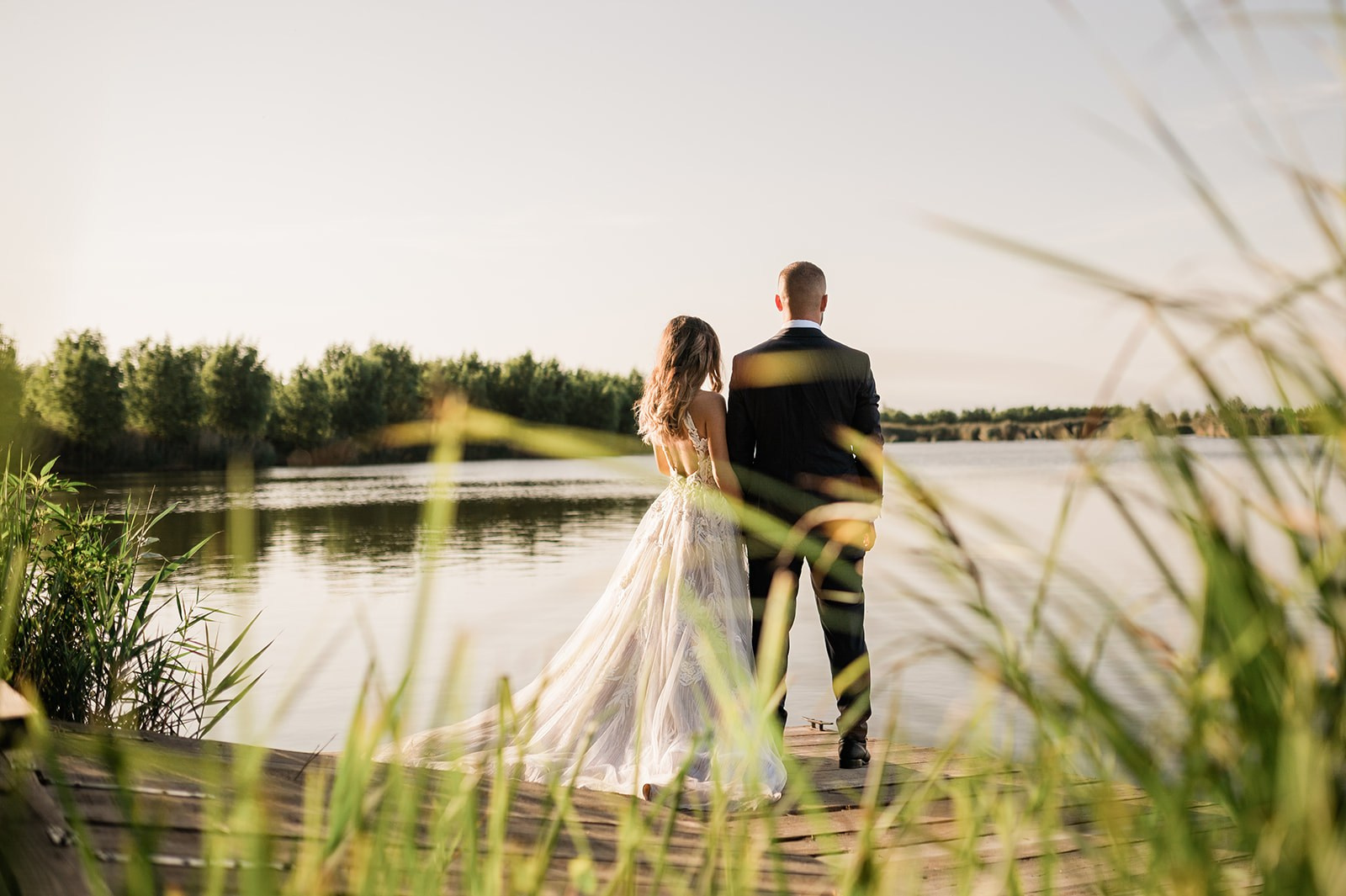 Sposa e sposo in abito da cerimonia osservano un lago al tramonto - scelta fotografo per foto di matrimonio.
