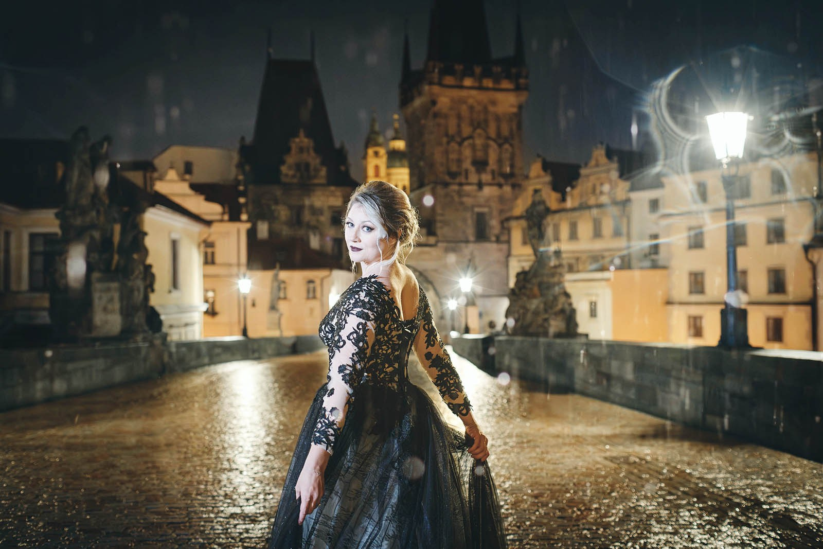 Bride in black wedding dress posing rainy gothic anniversary session nighttime Charles Bridge Prague.