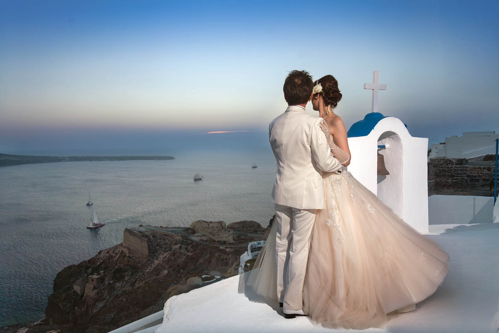Junji and Nao embracing at sunset at Oia’s westernmost tip, Santorini.