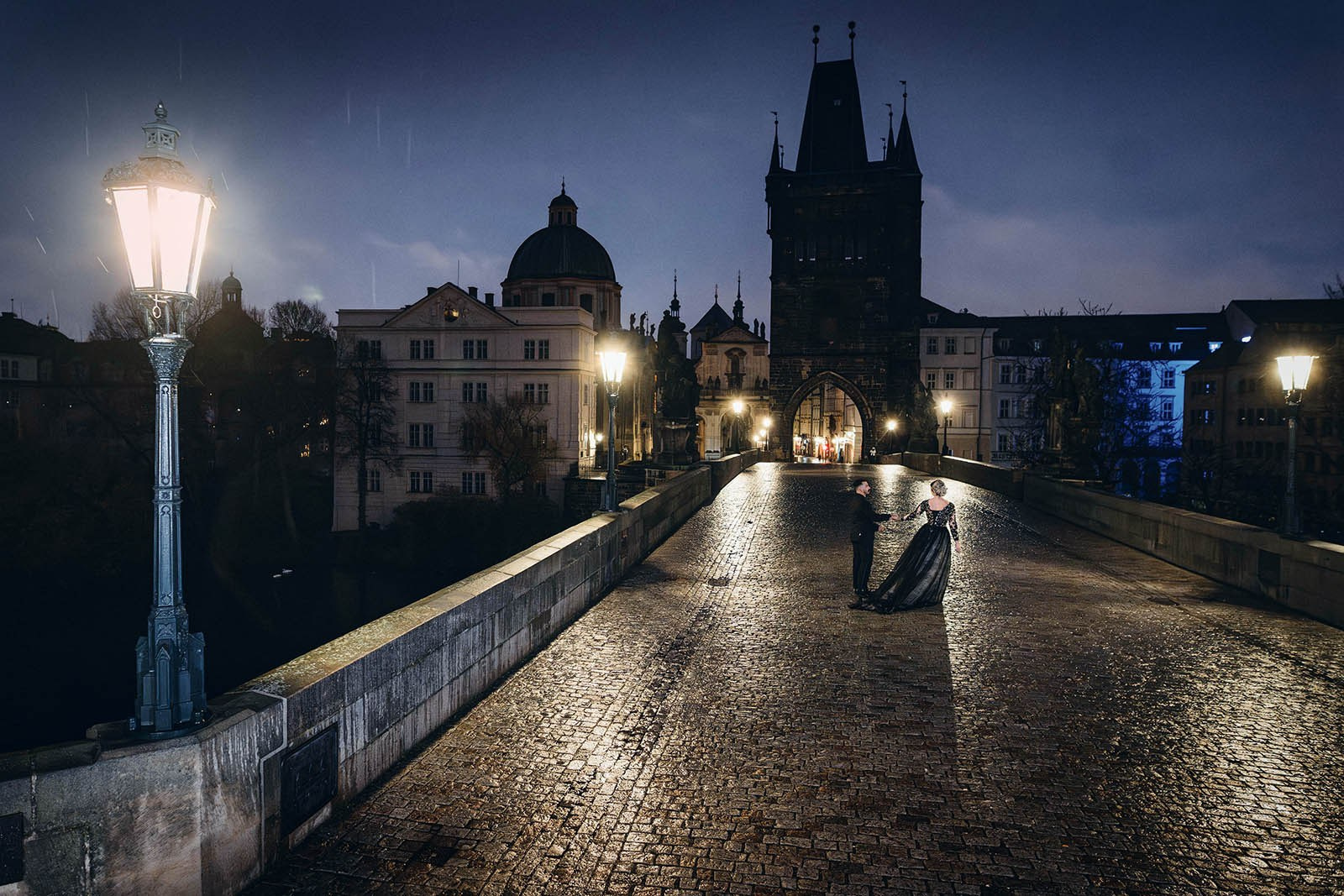 Couple in black dancing rainy gothic anniversary portrait nighttime Charles Bridge Prague.