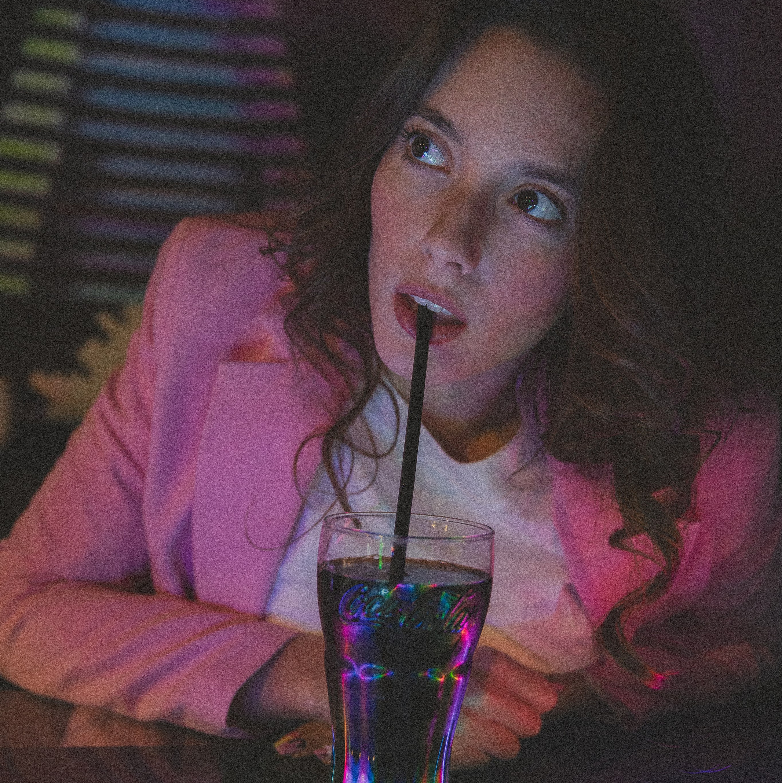 A woman sipping a drink during a cinematic photoshoot.