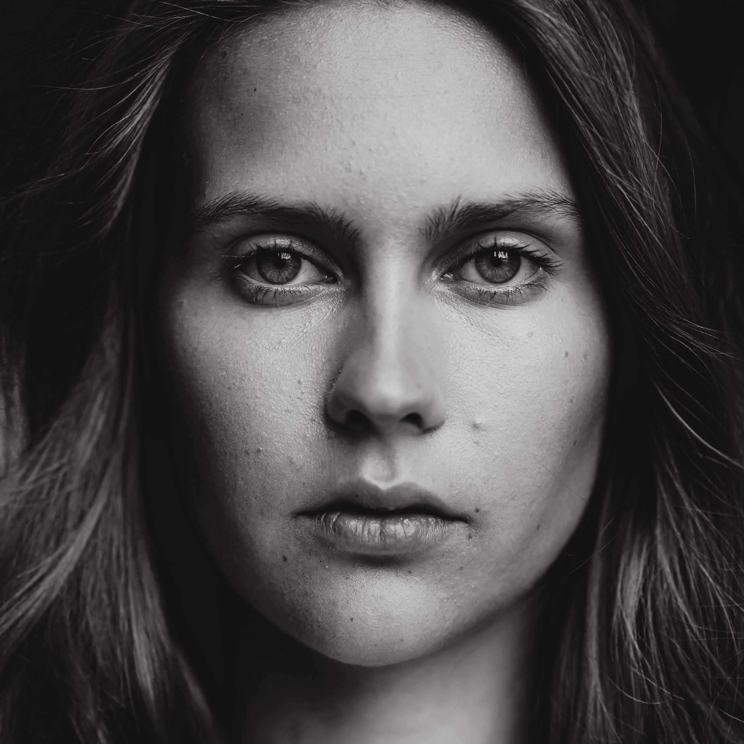 Black-and-white close-up portrait of a woman looking directly at the camera.