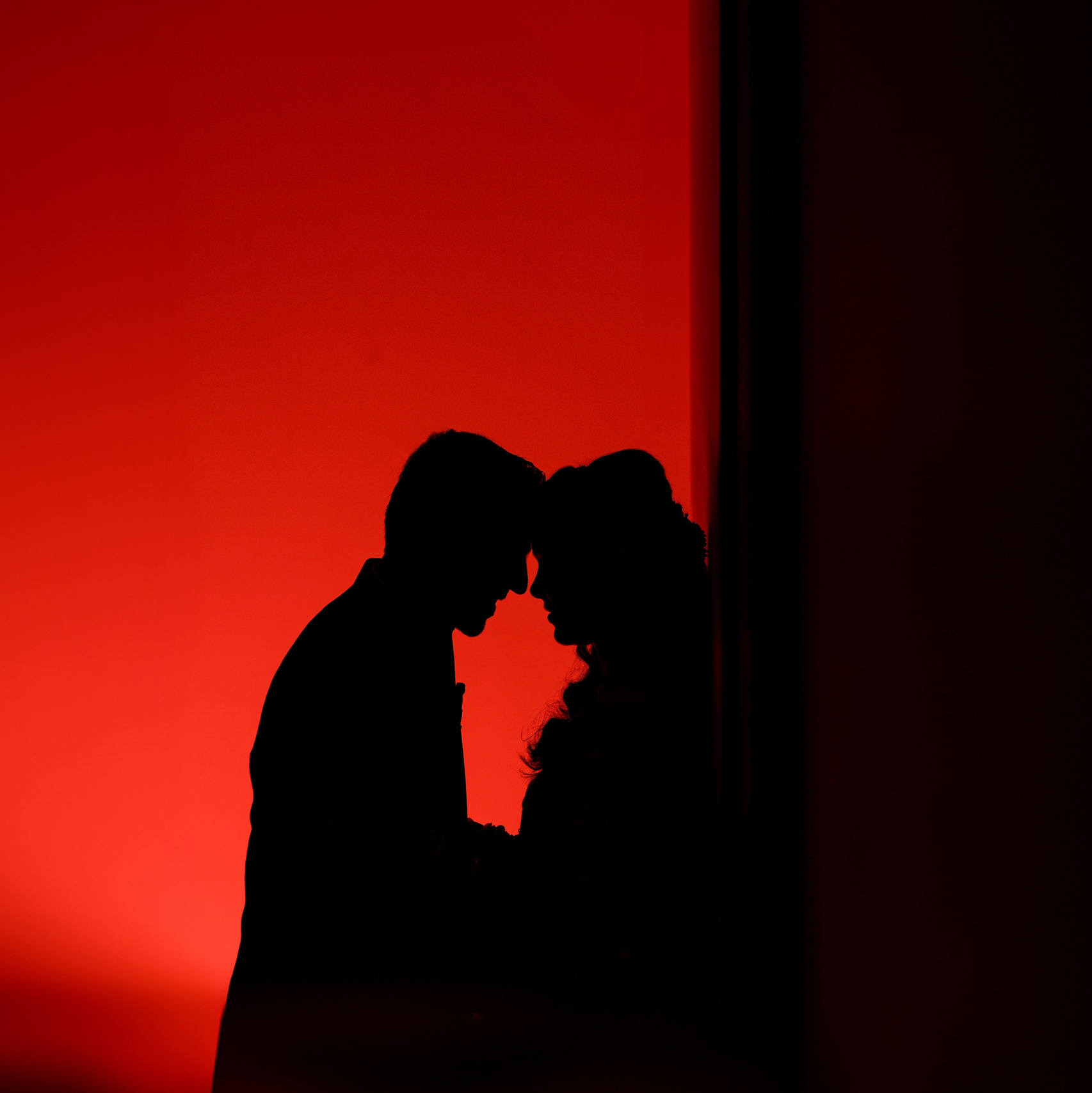 dramatic red-lit studio silhouette portrait of a couple with foreheads touching in Malleshwaram, Bengaluru