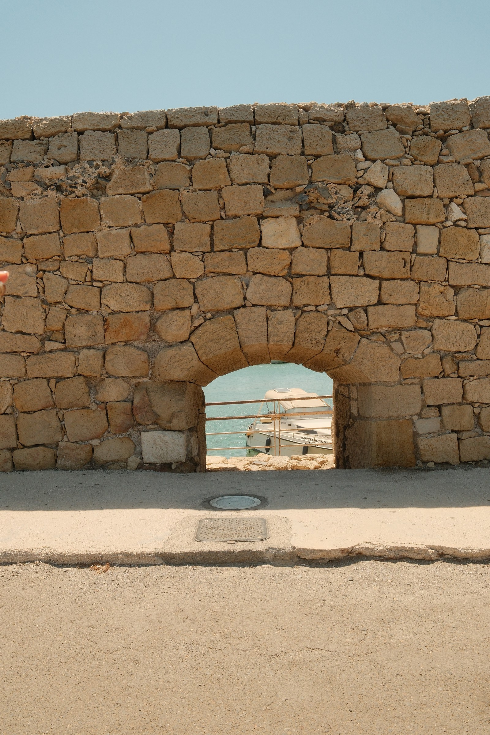 Stone harbour wall and boat at Heraklion, Crete, photographed with the Fujifilm Solis recipe.