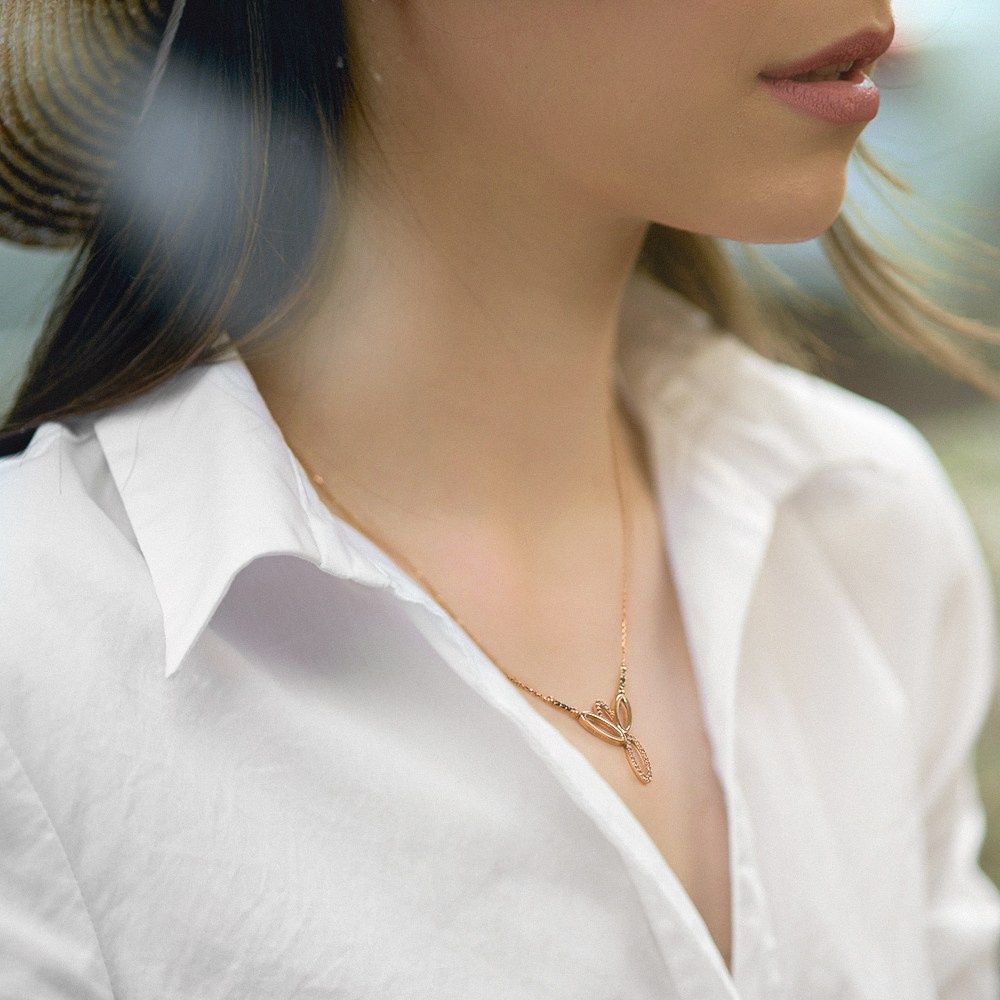 Devojka u beloj košulji nosi zlatnu ogrlicu.