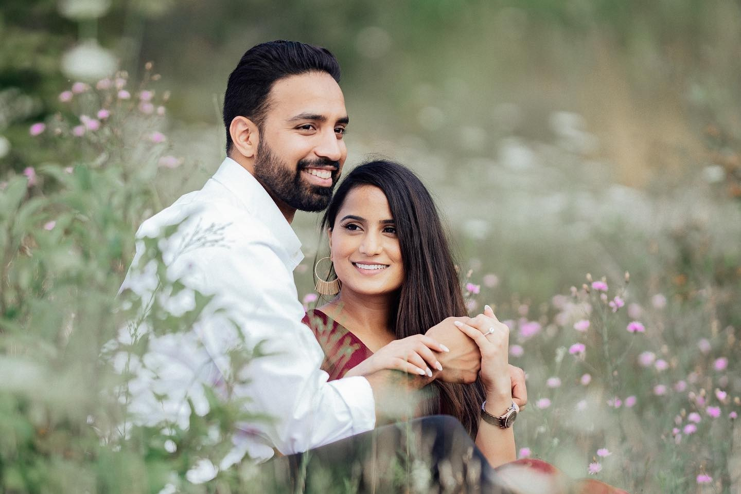 Bride and groom walking through golden wheat field during sunset