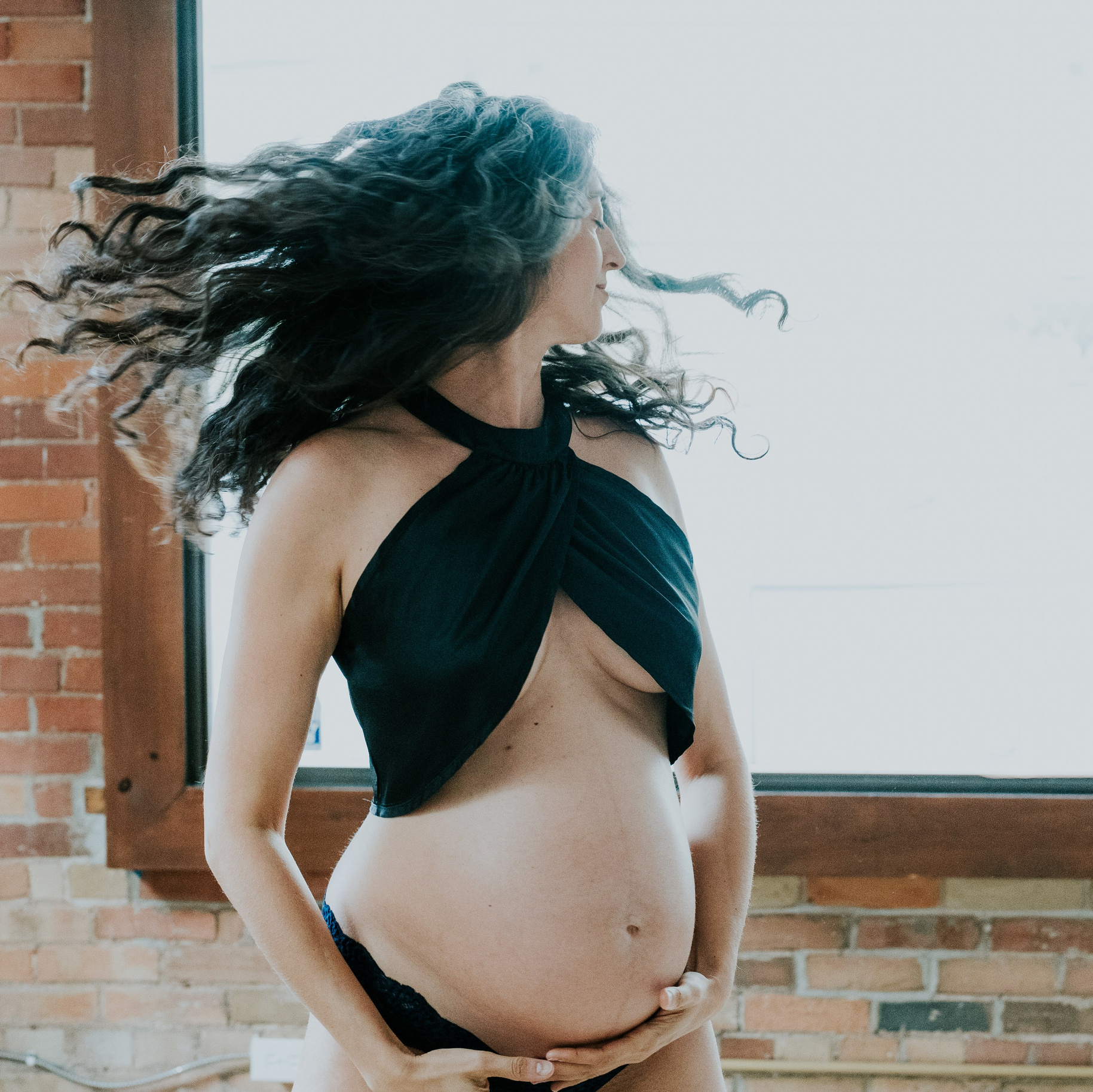 WOMAN IN BLACK BRA AND BARE PREGNANT BELLY SWINGING HER HAIR BACK AND FORTH