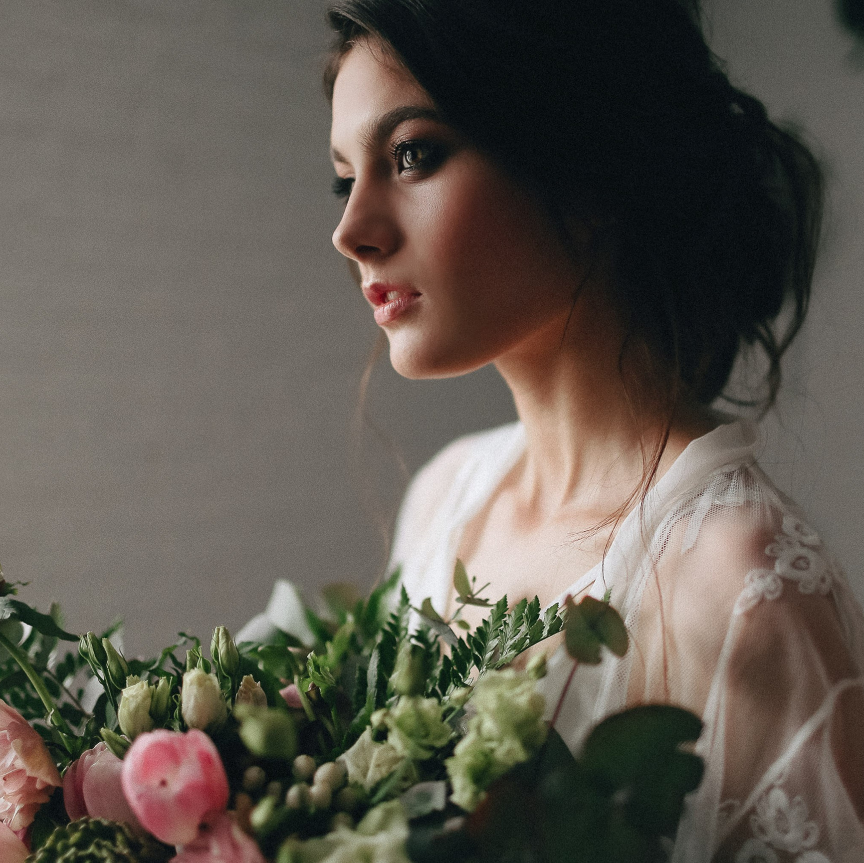 Bride indoors holding bouquet, side profile