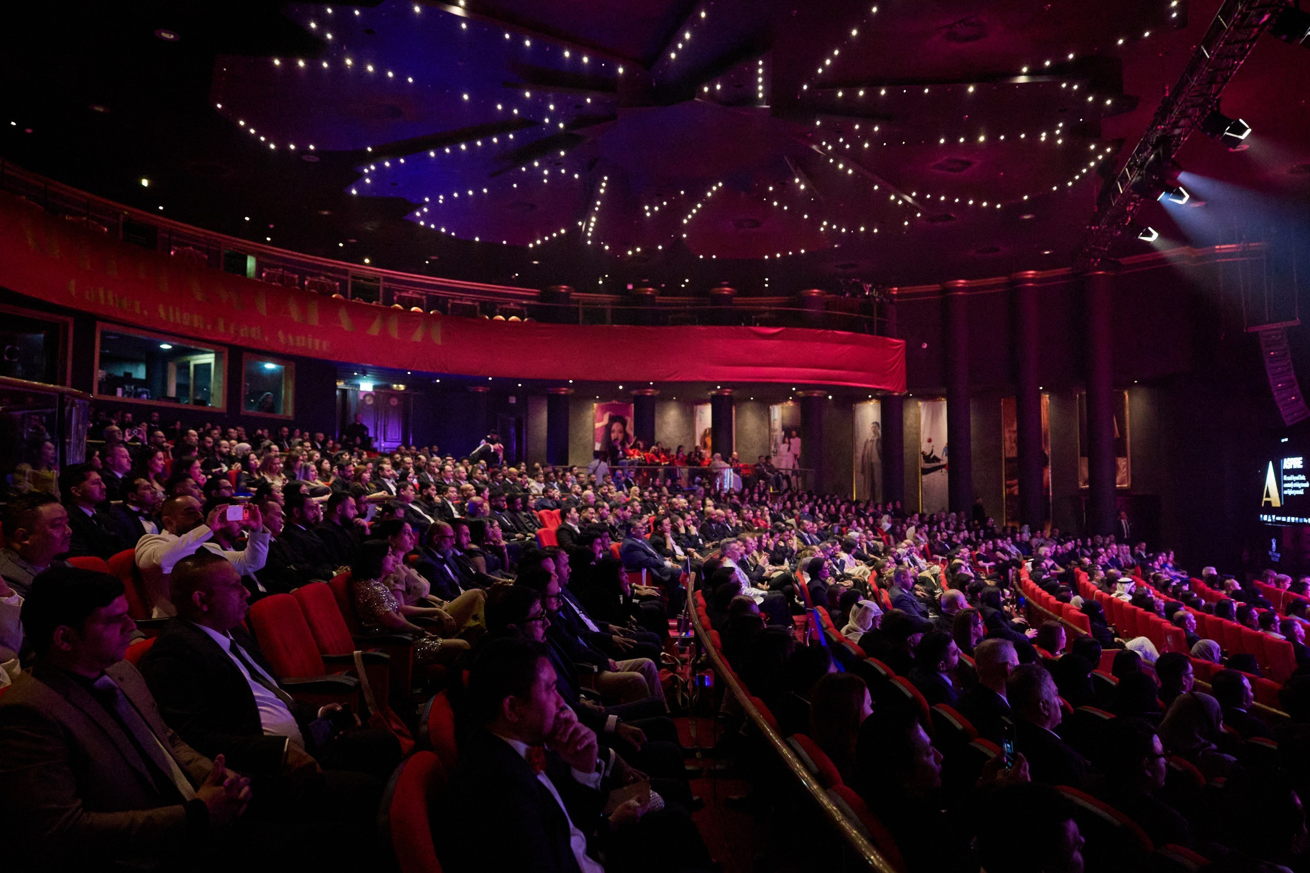 Large corporate audience inside a theatre prepared for professional event coverage in Dubai