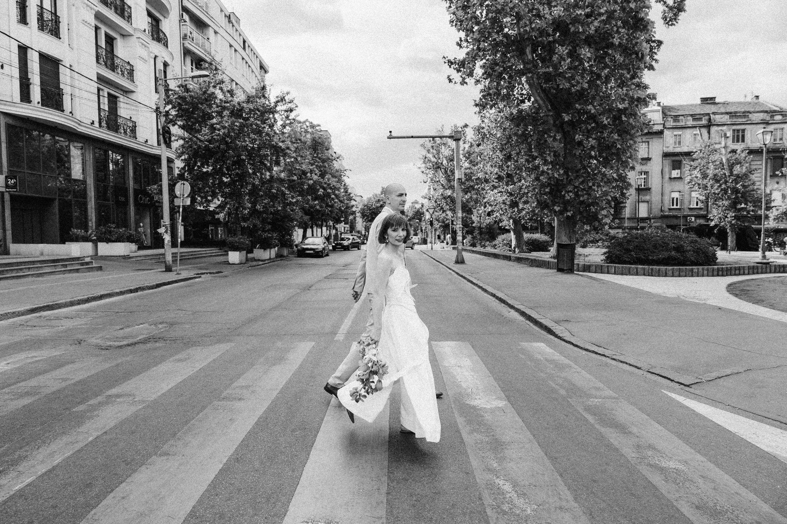 Maldenci prelaze pešački prelaz. Mlada gelda u fotografa.