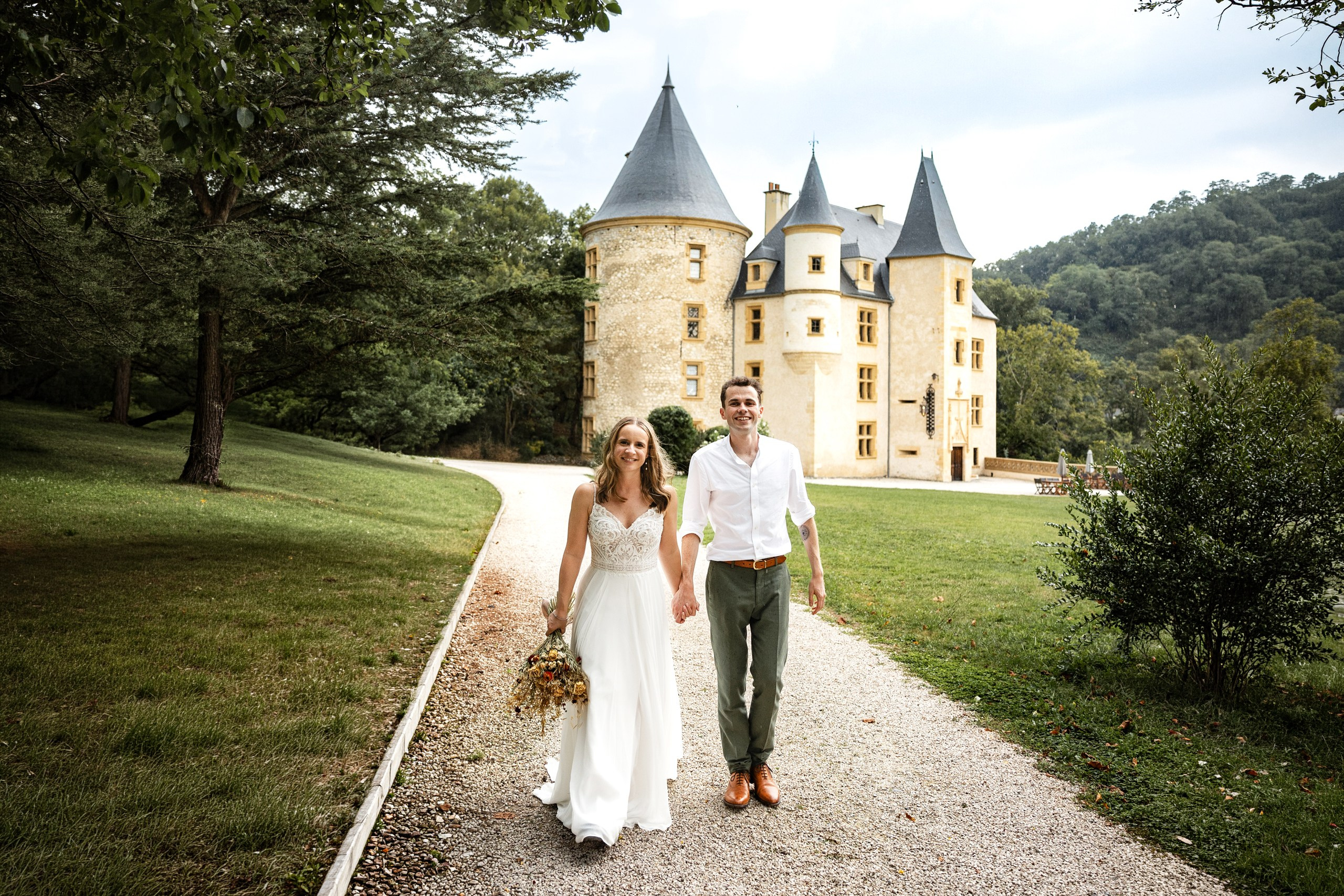 Elegant château estate wedding in Southwest France with couple embracing in front of historic architecture.