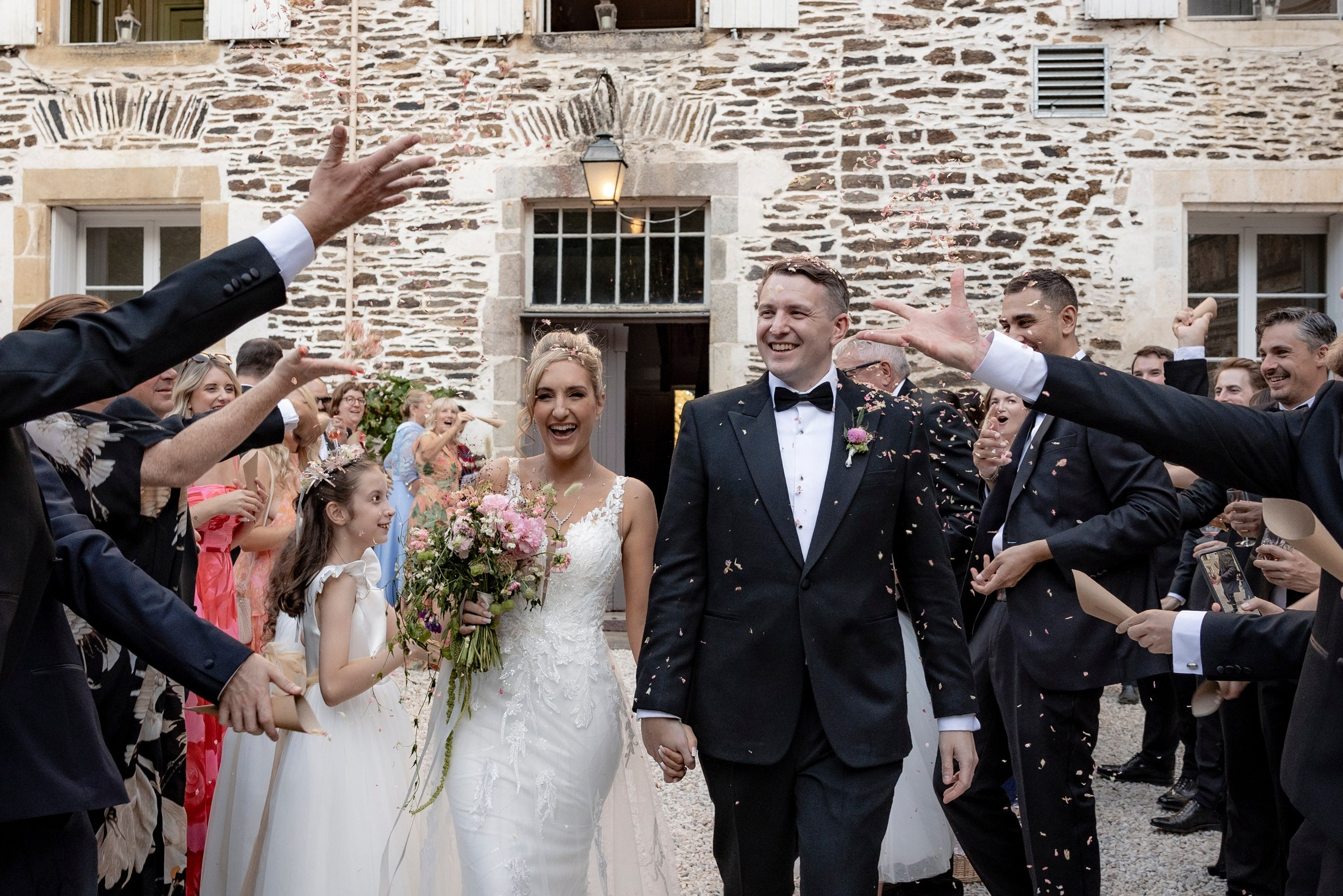 Bride and groom walking through guests during a joyful château wedding celebration in France.