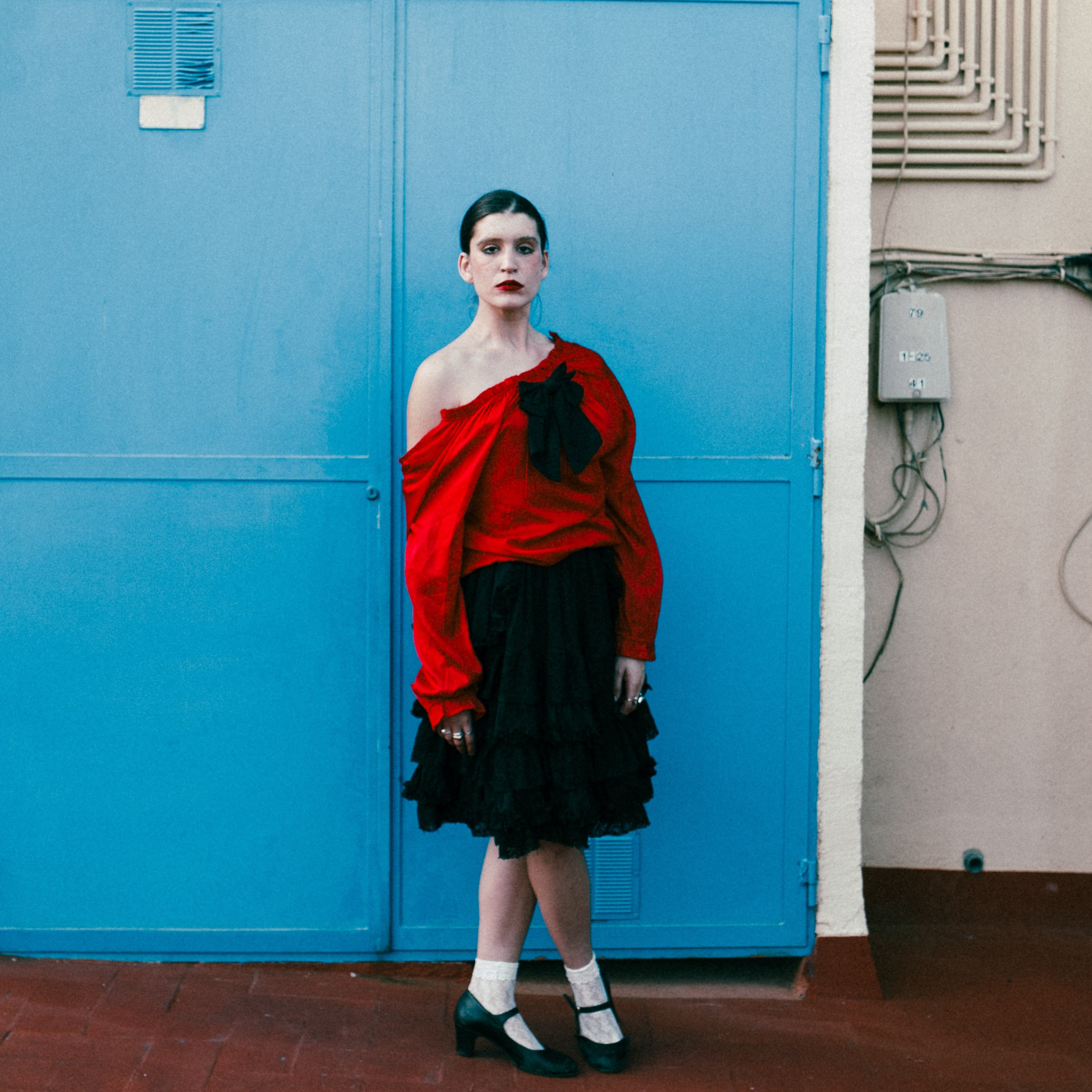 portrait of a young woman in red top against blue wall, outdoor portrait session Barcelona