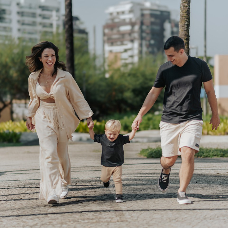 Família correndo e sorrindo em ensaio fotográfico na Barra da Tijuca, Rio de Janeiro