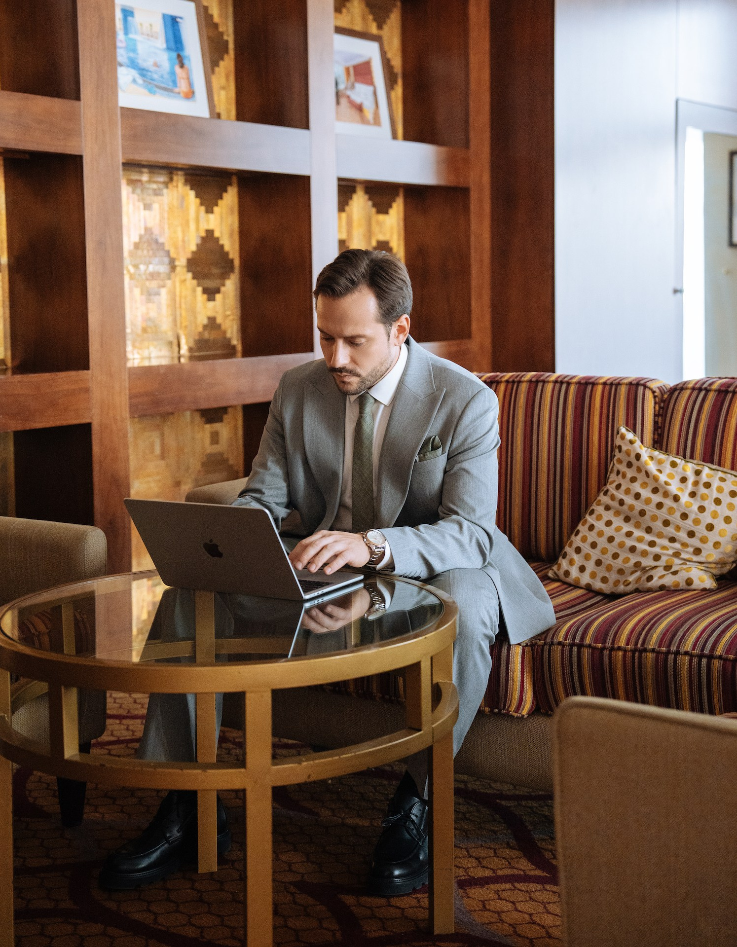 Гость в деловой одежде работает за ноутбуком в лобби отеля
