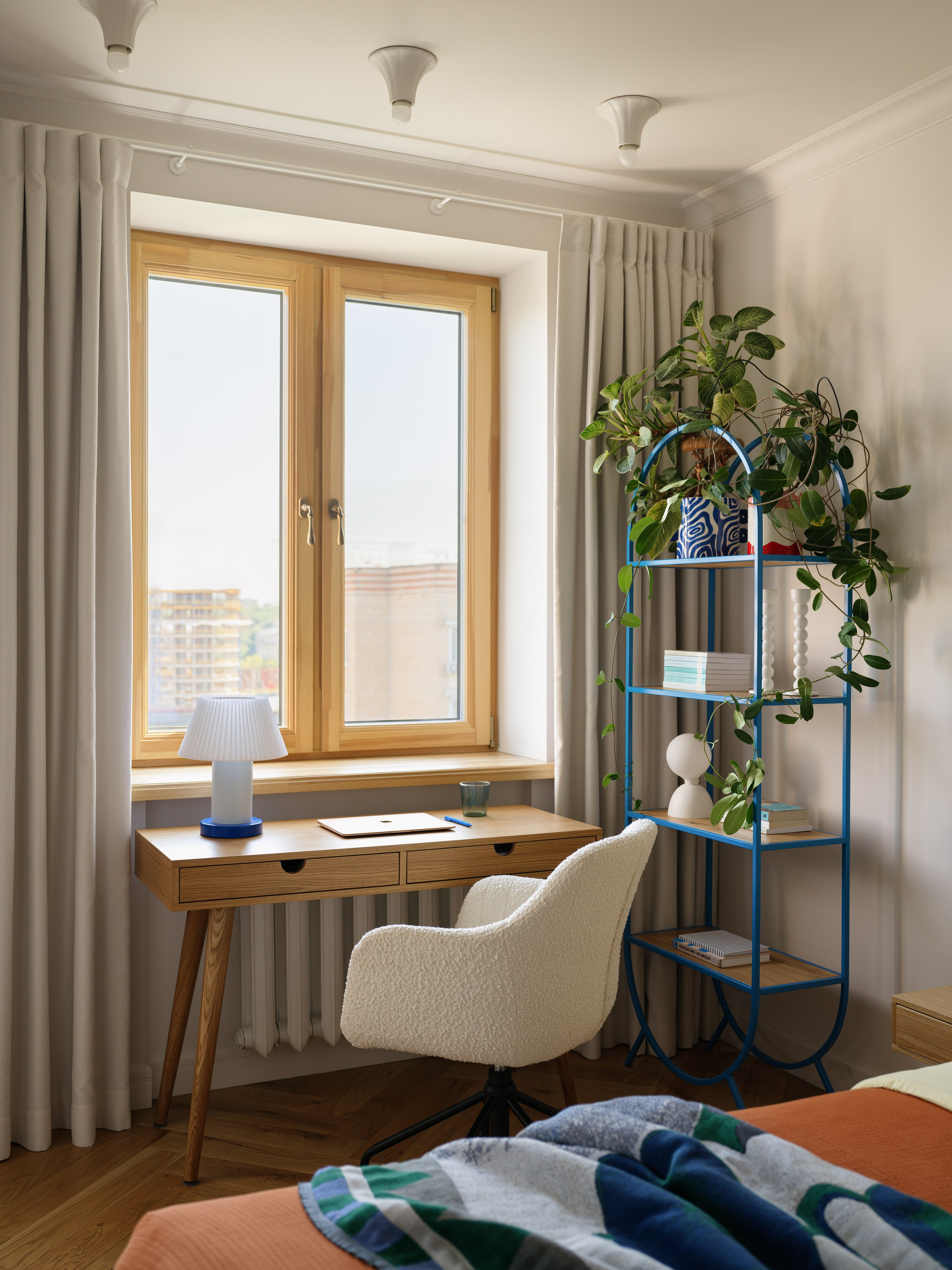 Рабочий стол из массива дуба и кресло-букле напротив окна в спальне.